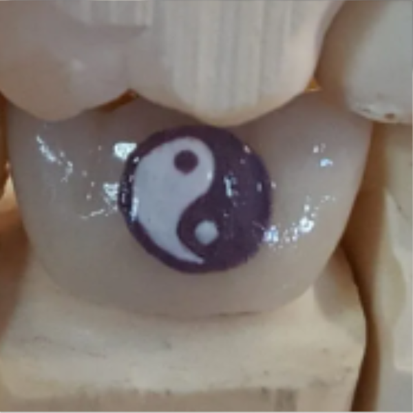 Close-up of a yin-yang symbol painted on a Buddha statue's chest.