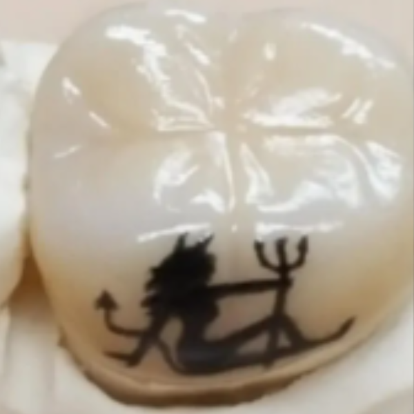 A close-up of a white round object, possibly a soap or a decorative item, with a black silhouette of a mermaid holding a trident printed on it.