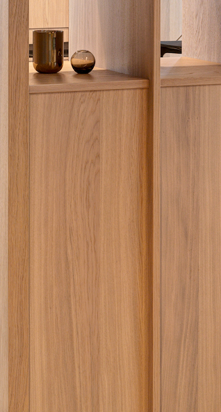 Two small glass vases on a wooden shelf against a wooden background.