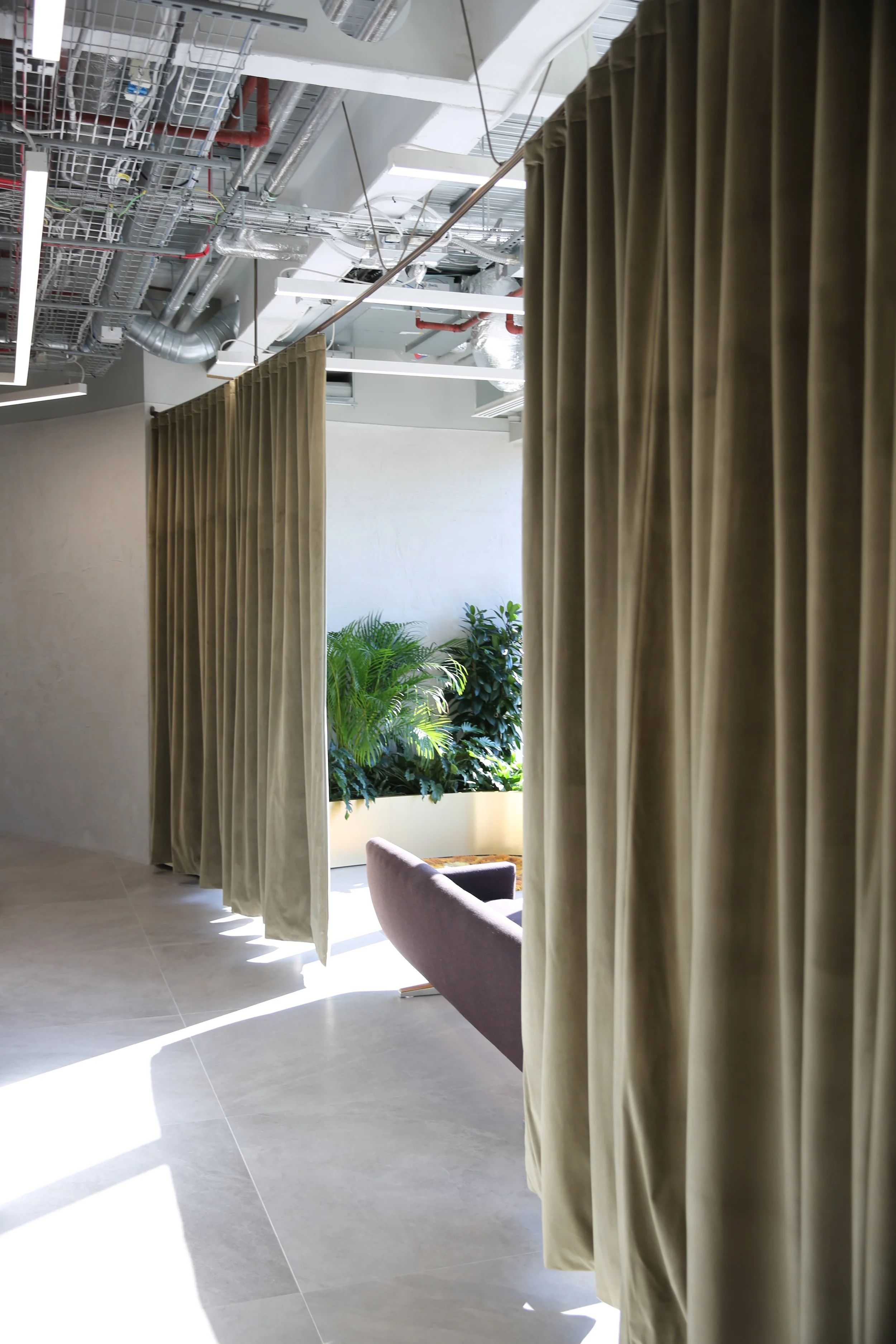 Interior room with beige curtains, potted greenery, and sunlight streaming through a window.