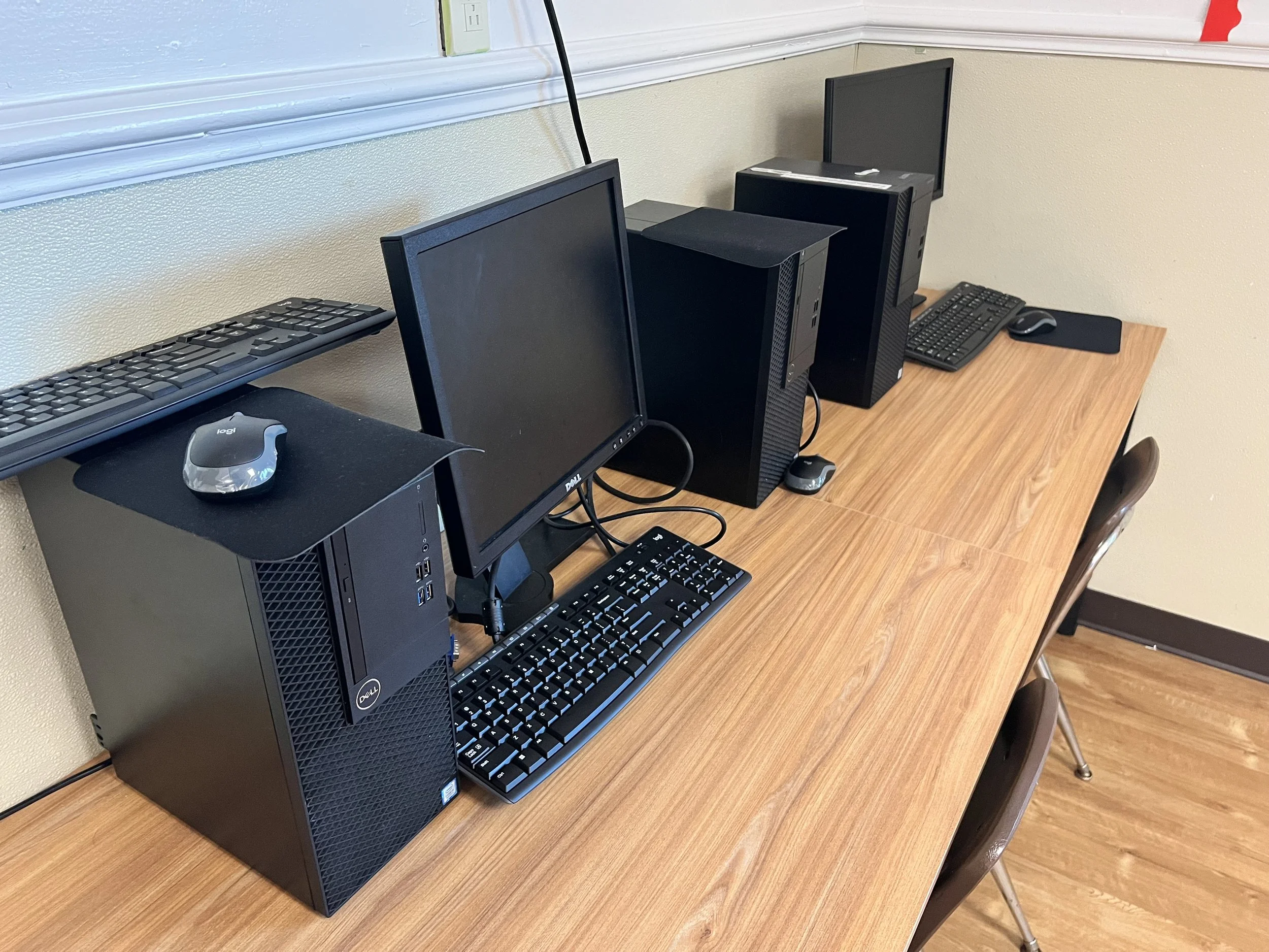 A desktop computer setup on a wooden table with a monitor, keyboard, mouse, and a tower case.