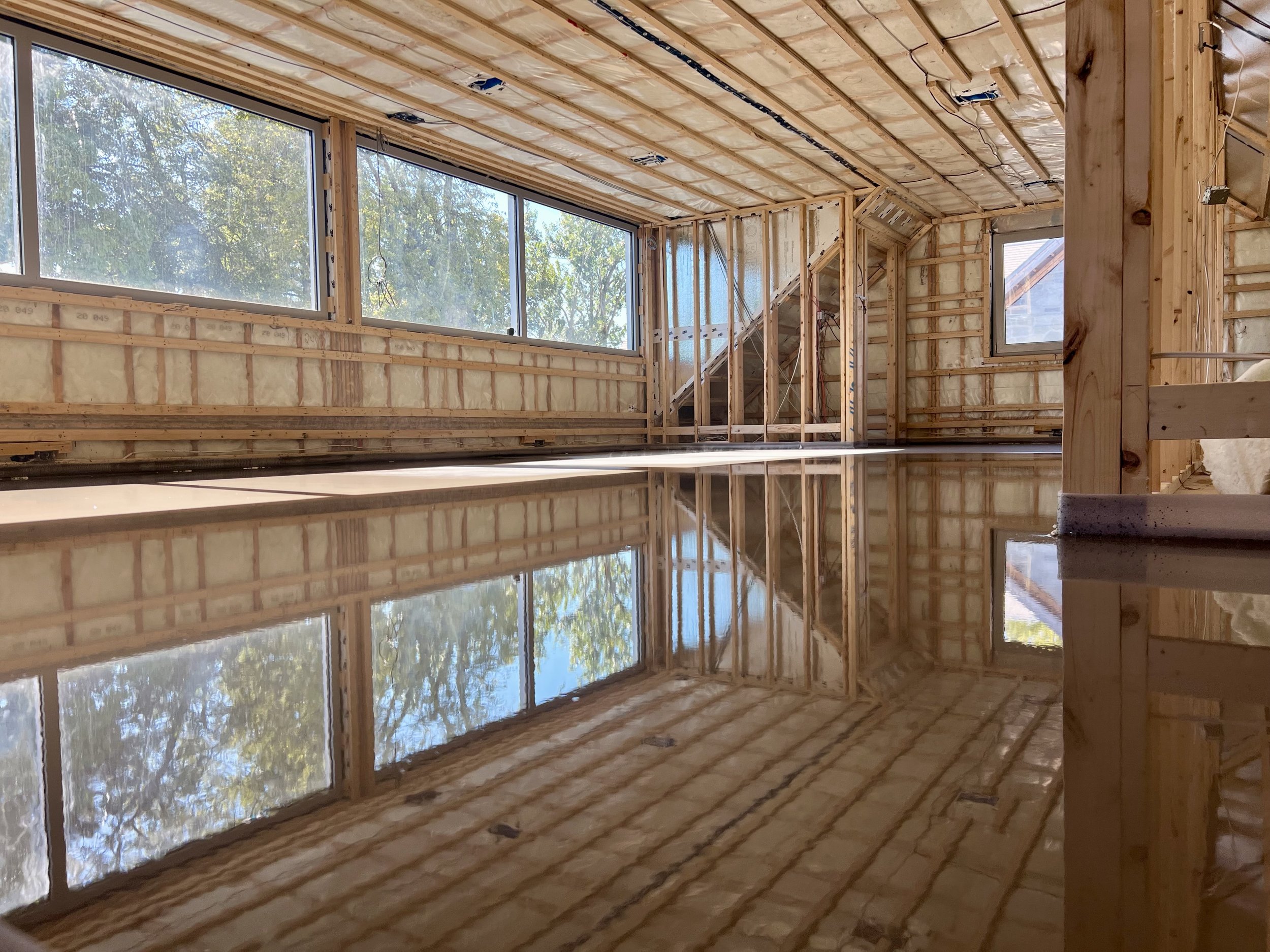 Intérieur d'une maison en construction avec fenêtres, structure en bois et isolation.