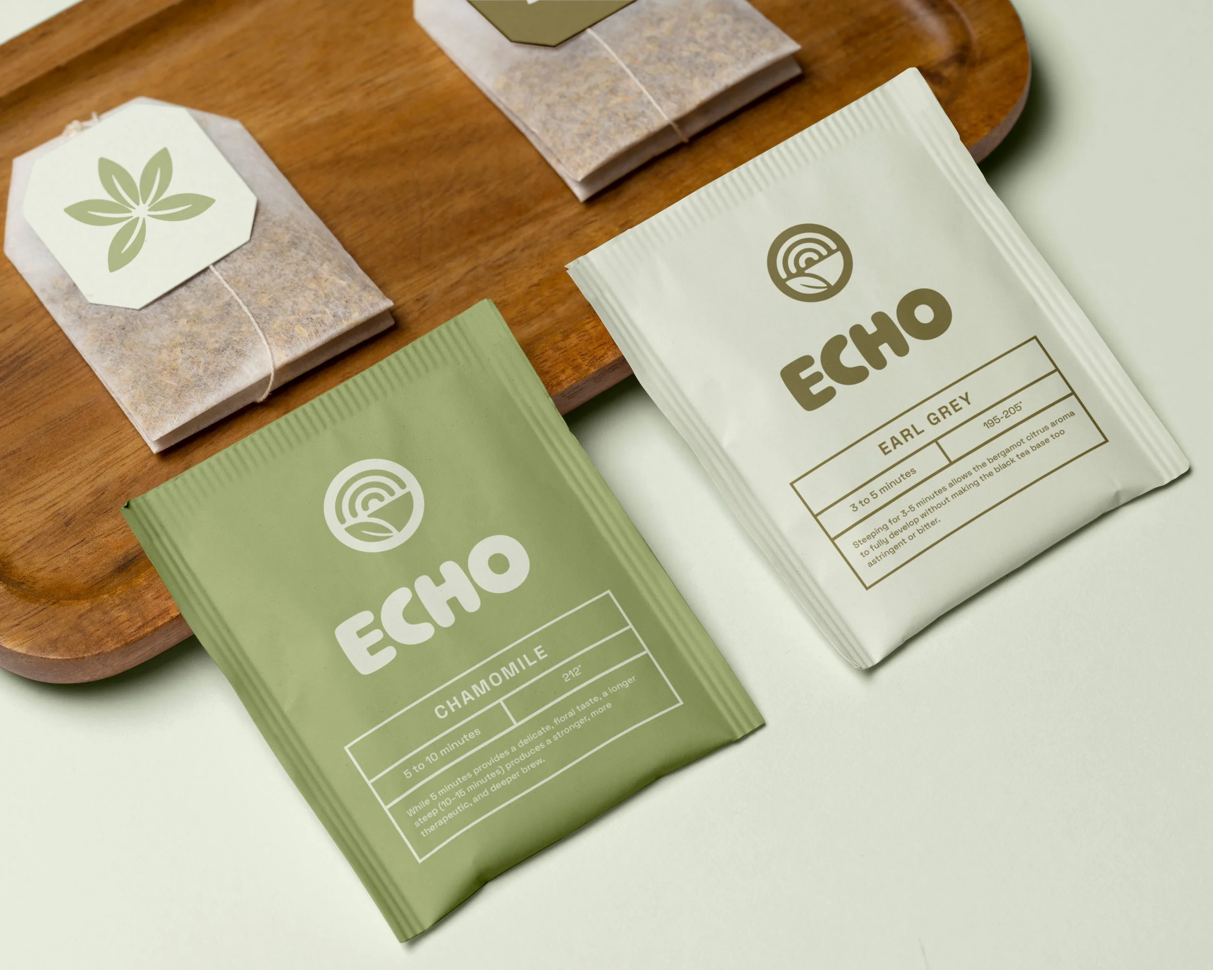 Several packets of loose-leaf tea with the brand name 'ECHO' on two packets, showing different flavors: Earl Grey and Chamomile, placed on a wooden tray.