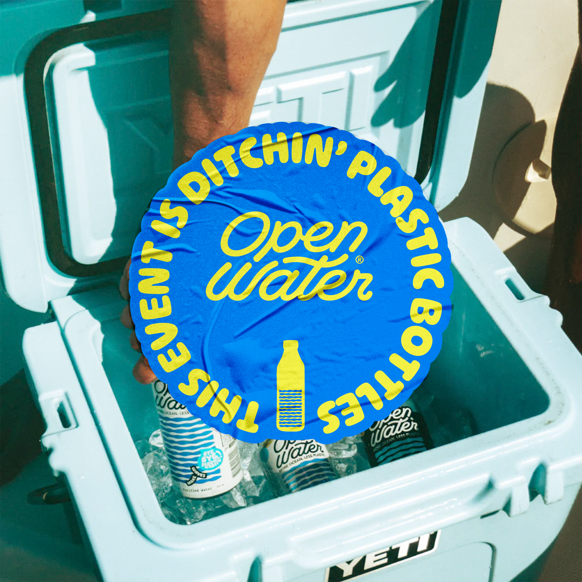 Close-up of a blue sticker on a water bottle inside a vending machine with the words "Water is Open" written in yellow.