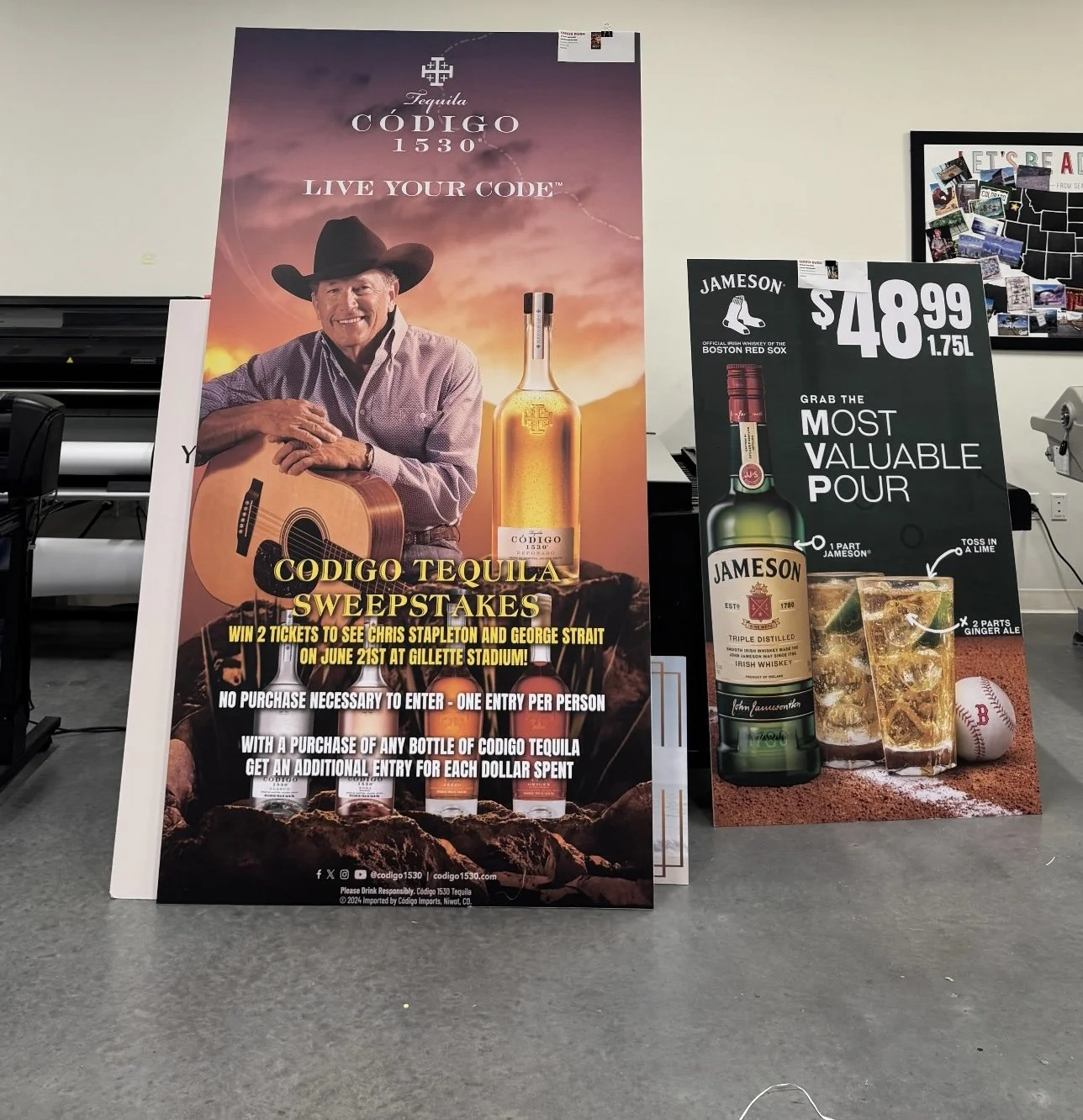 Promotional posters for Codigo Tequila and Jameson Irish Whiskey. The Codigo Tequila poster features a smiling man in a cowboy hat holding a guitar, with a sunset background and a large tequila bottle, advertising a sweepstakes with a chance to win tickets to see Chris Stapleton and George Strait. The Jameson Whiskey poster displays a bottle of Jameson Irish Whiskey with a cocktail, baseball, and lime, promoting a special price of $48.99 for 1.75 liters.