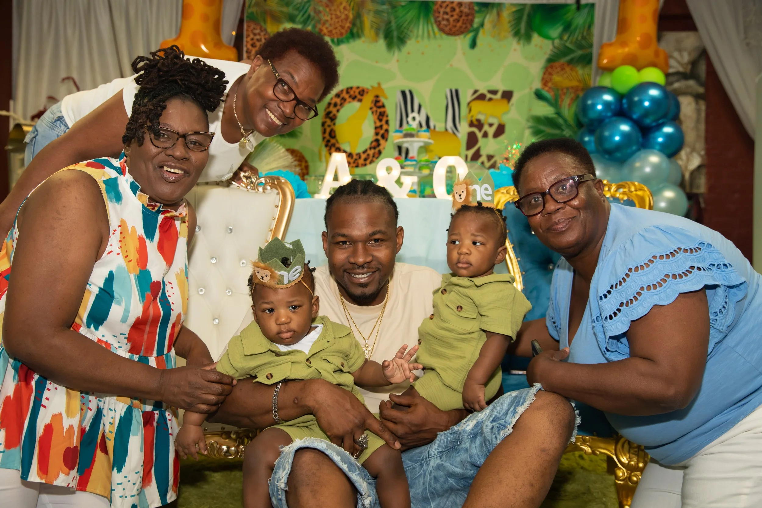 Group of six people, including two children, at a jungle-themed birthday celebration with balloons and decorations.