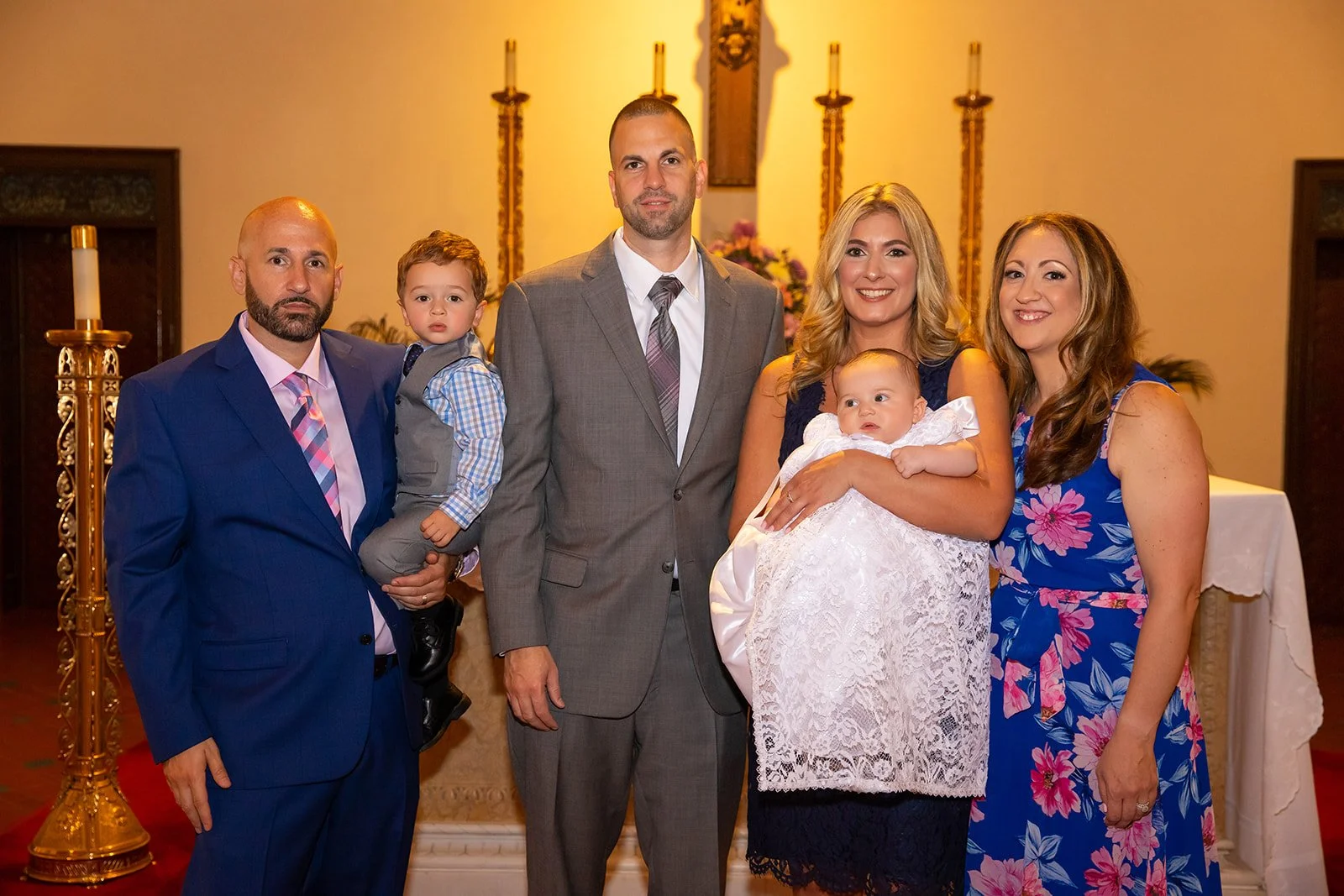 Group of six people, including two children, standing inside a church with religious decorations on the wall behind them.