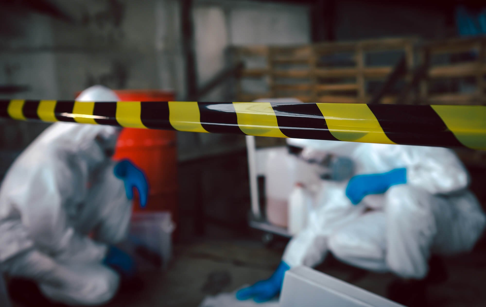 Yellow and black striped caution tape in a storage area with bins and boxes in the background.