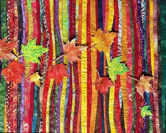 Colorful fabric background with vertical stripes and fabric autumn leaves scattered across.