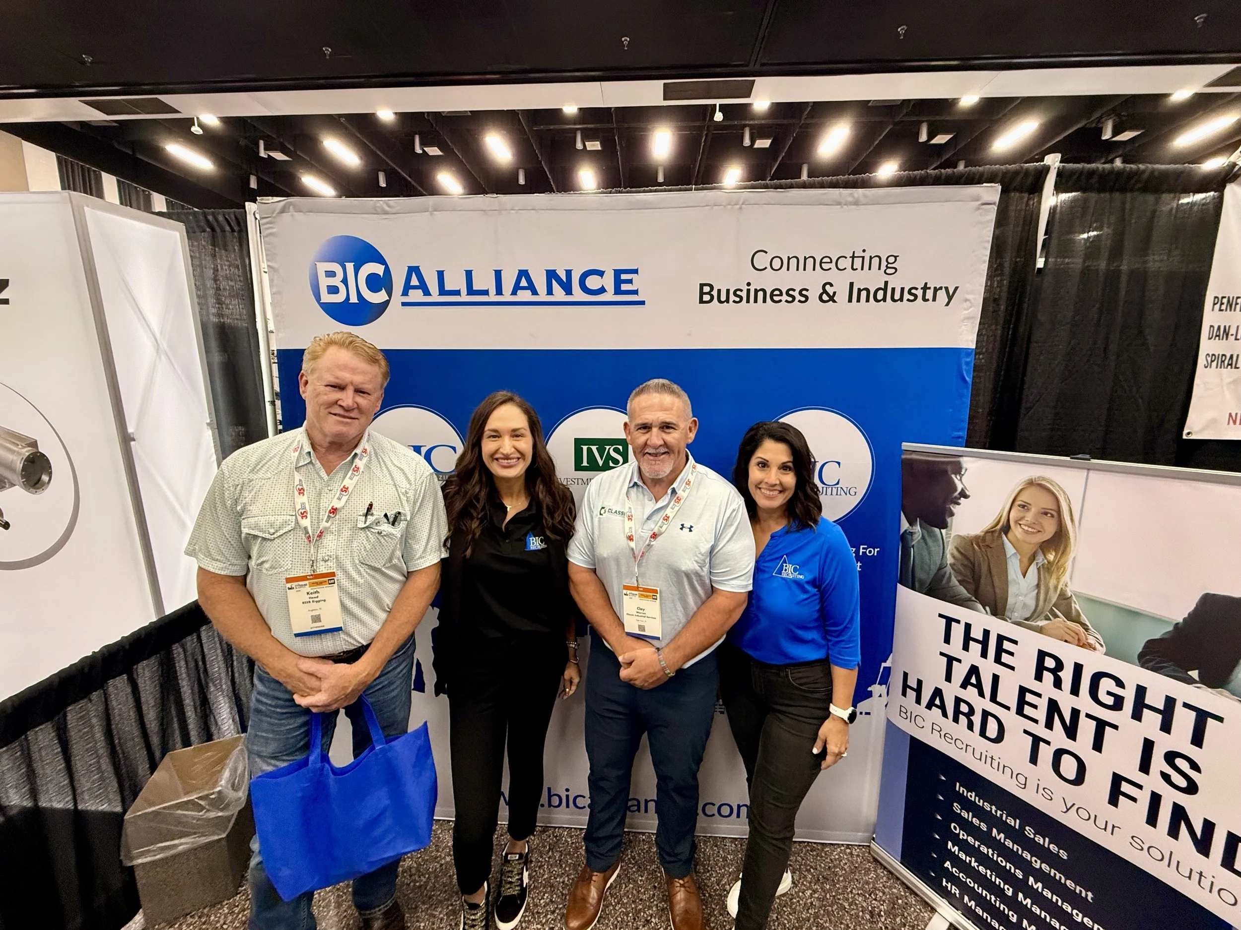 Four people standing in front of a BIC Alliance banner at a business conference, smiling for the photo.