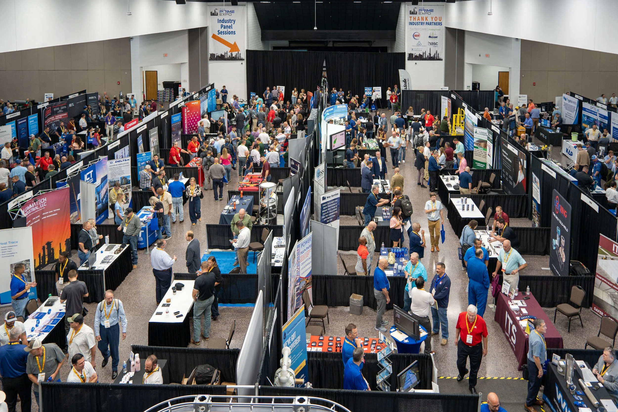 Crowded industry expo with numerous booths and attendees in a large hall, featuring banners and displays.