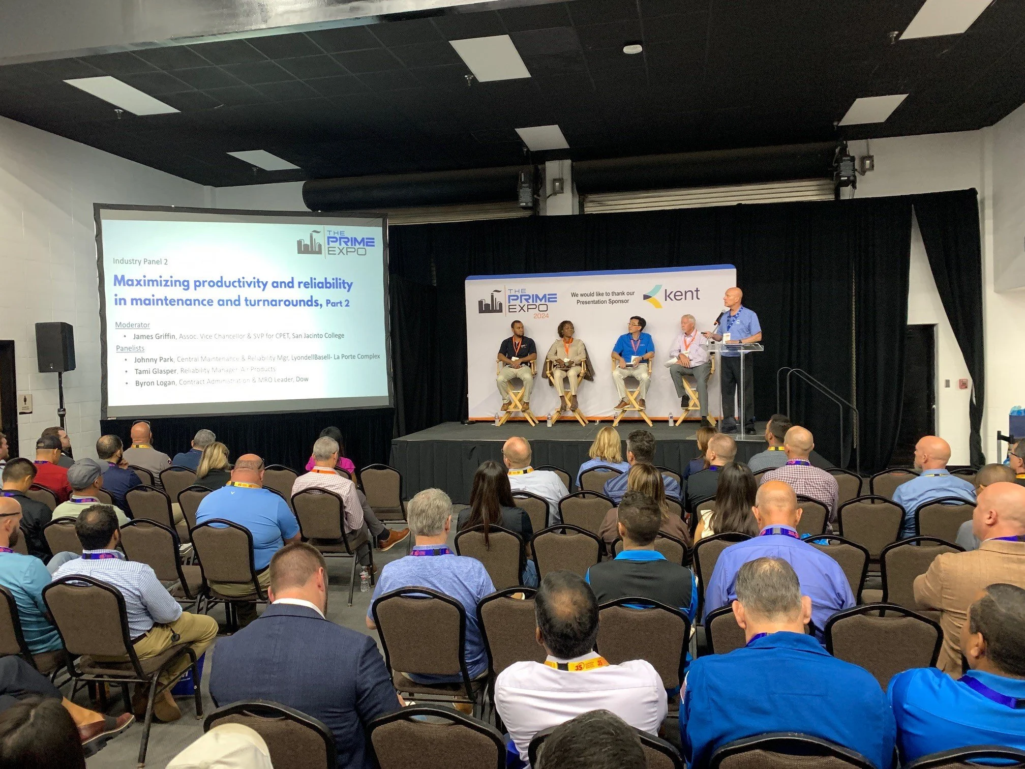 A panel discussion at The Prime Expo 2024 with five participants on stage, a large screen displaying a presentation titled 'Maximizing productivity and reliability in maintenance and turnarounds, Part 2,' and an audience seated in rows.