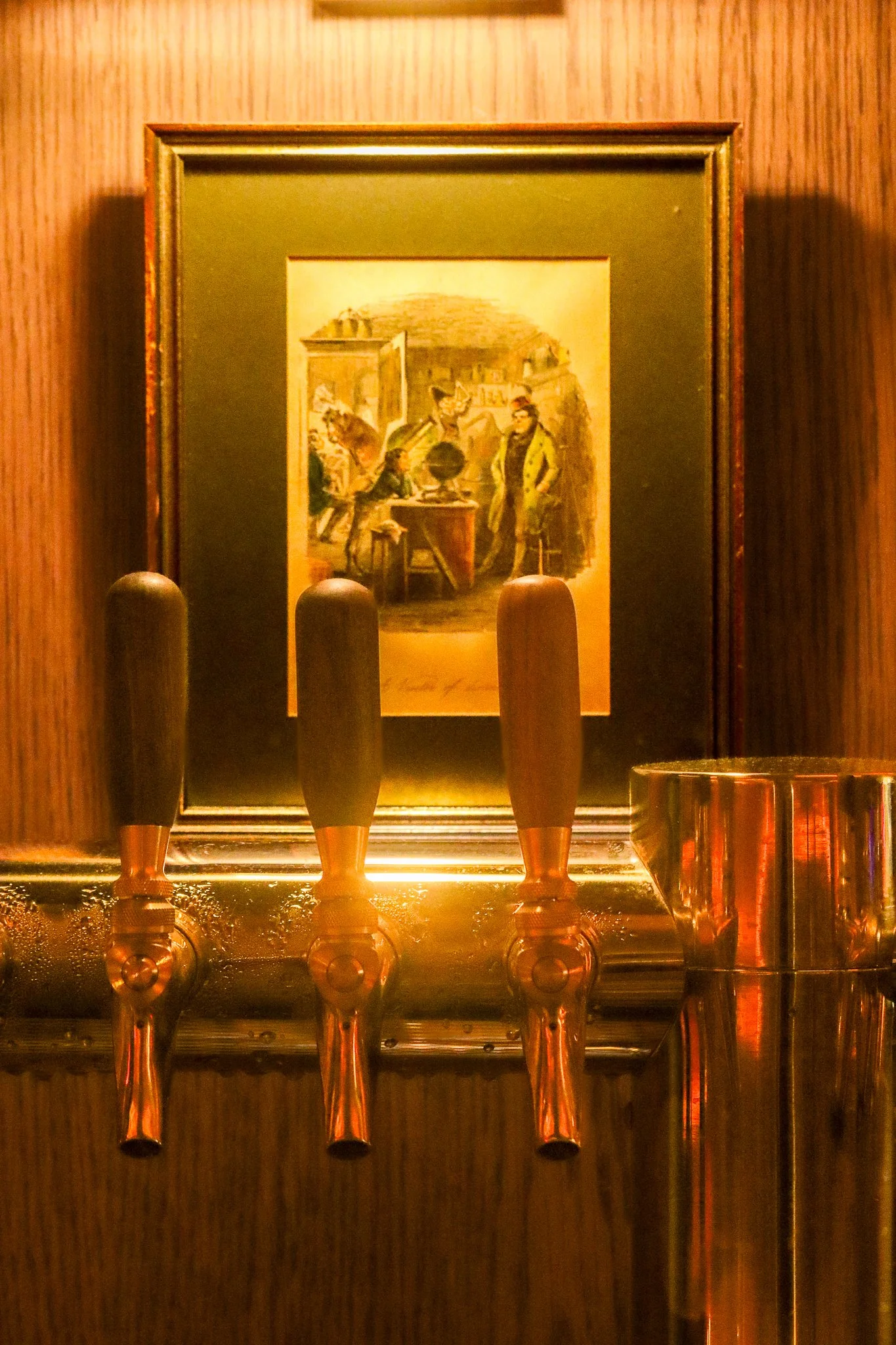 A framed picture of a historical scene with two men, one standing and one sitting, inside a room with wooden furniture and decorations. The photo is taken through a glass display case, reflecting objects in the room.