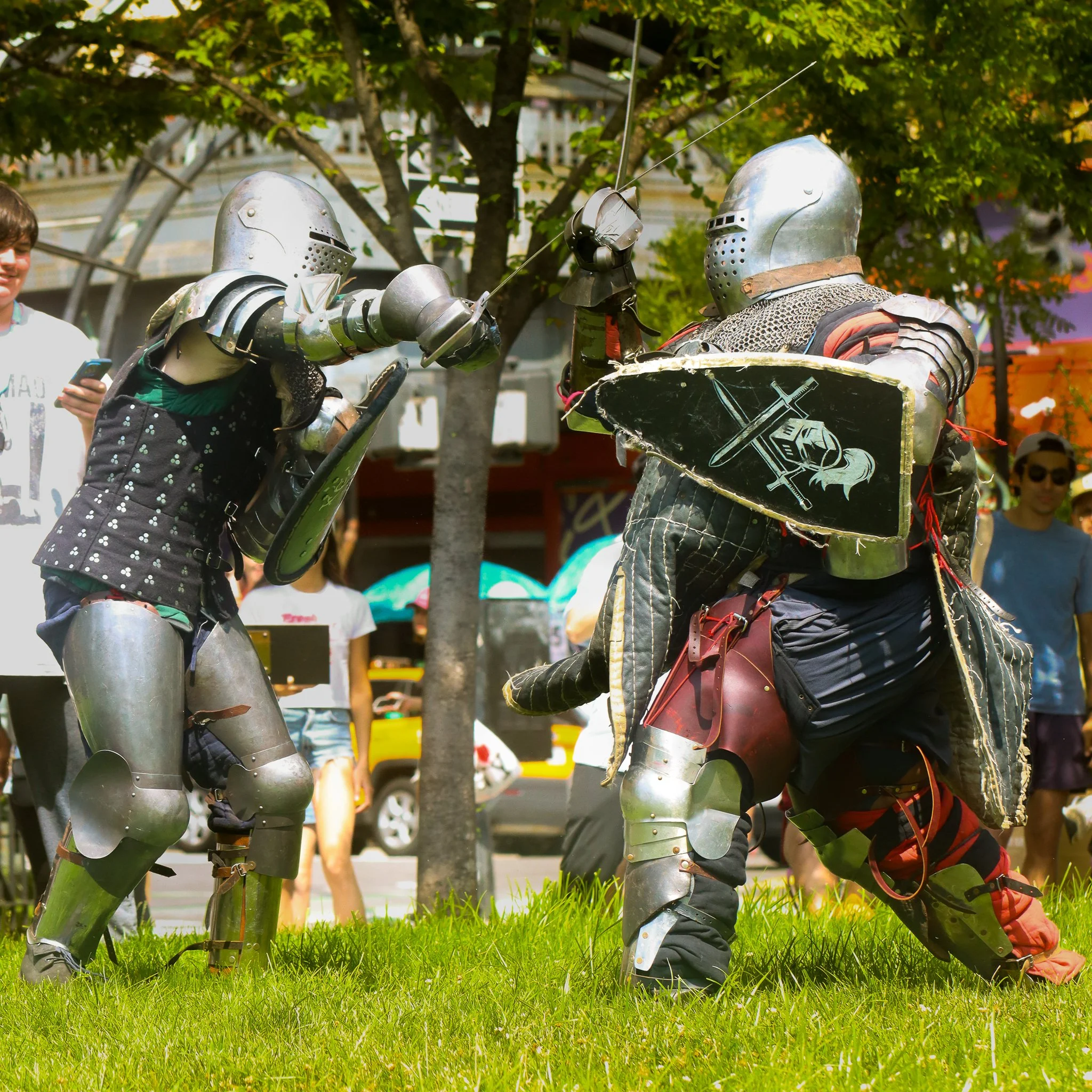 Two people dressed in medieval knight costumes shaking hands in a park.