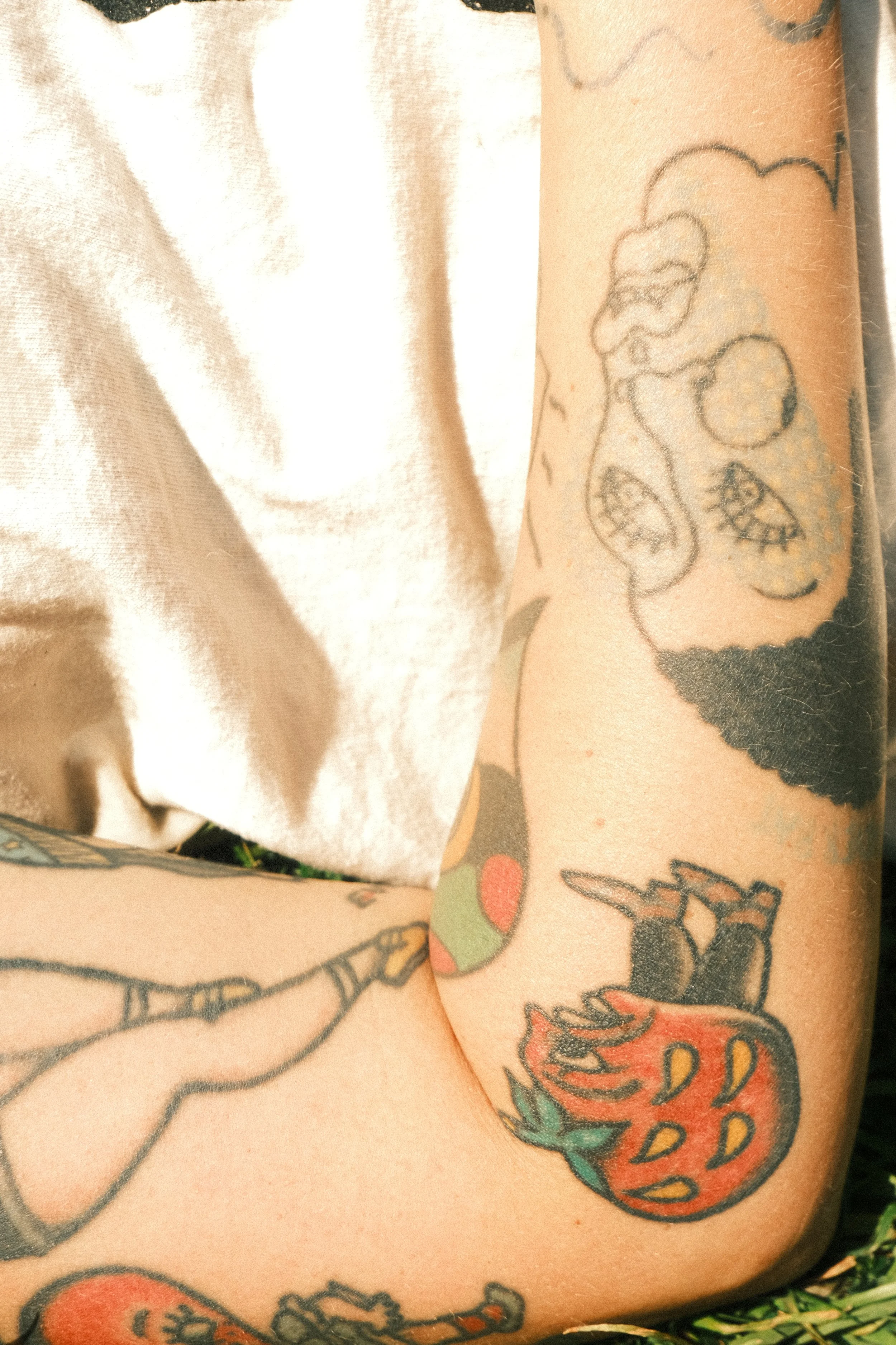 Close-up of a person's arm with tattooed illustrations, including a heart with flames and other designs.