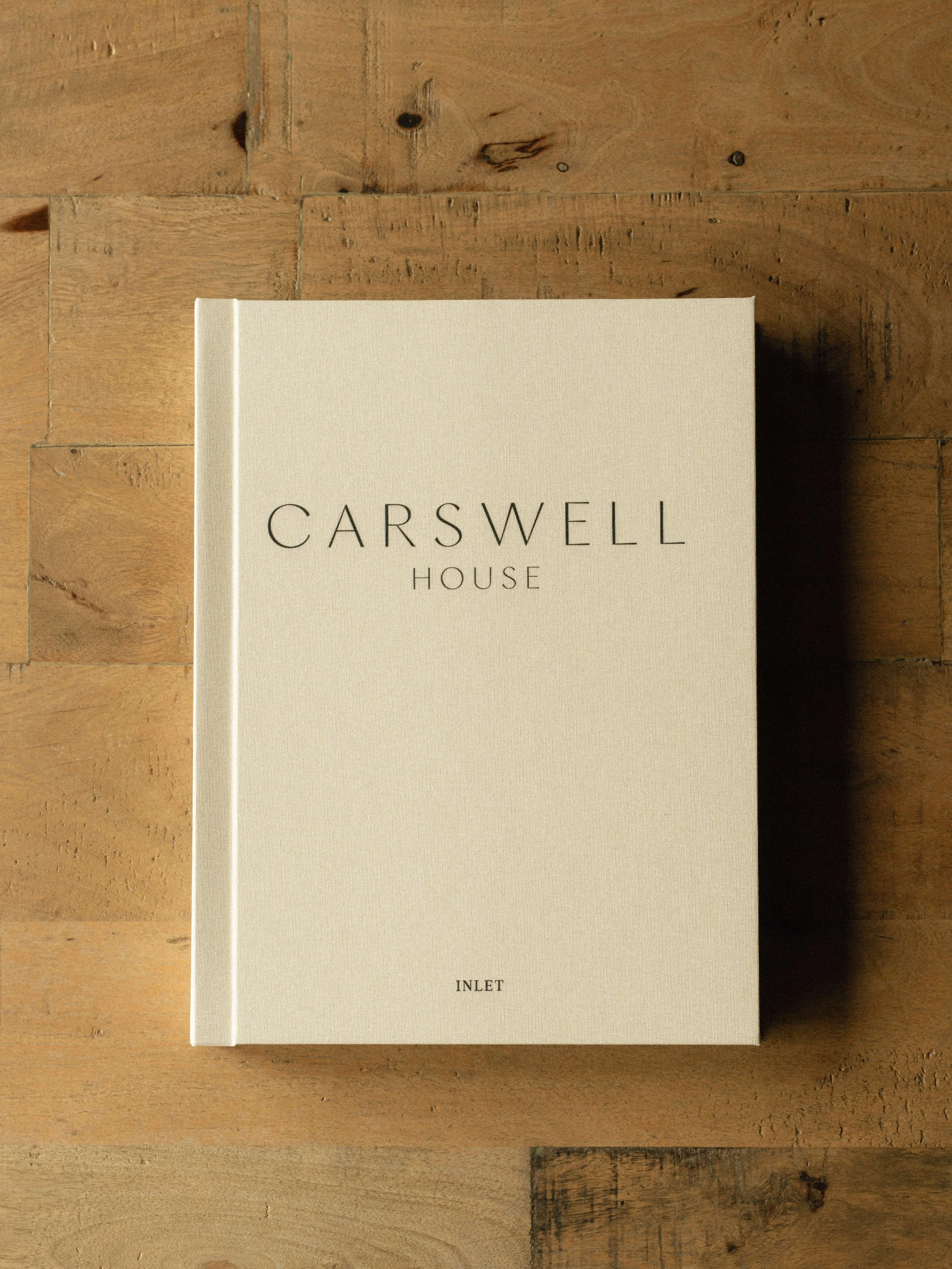A book titled 'Carswell House' with the word 'Inlet' at the bottom, placed on a wooden surface.