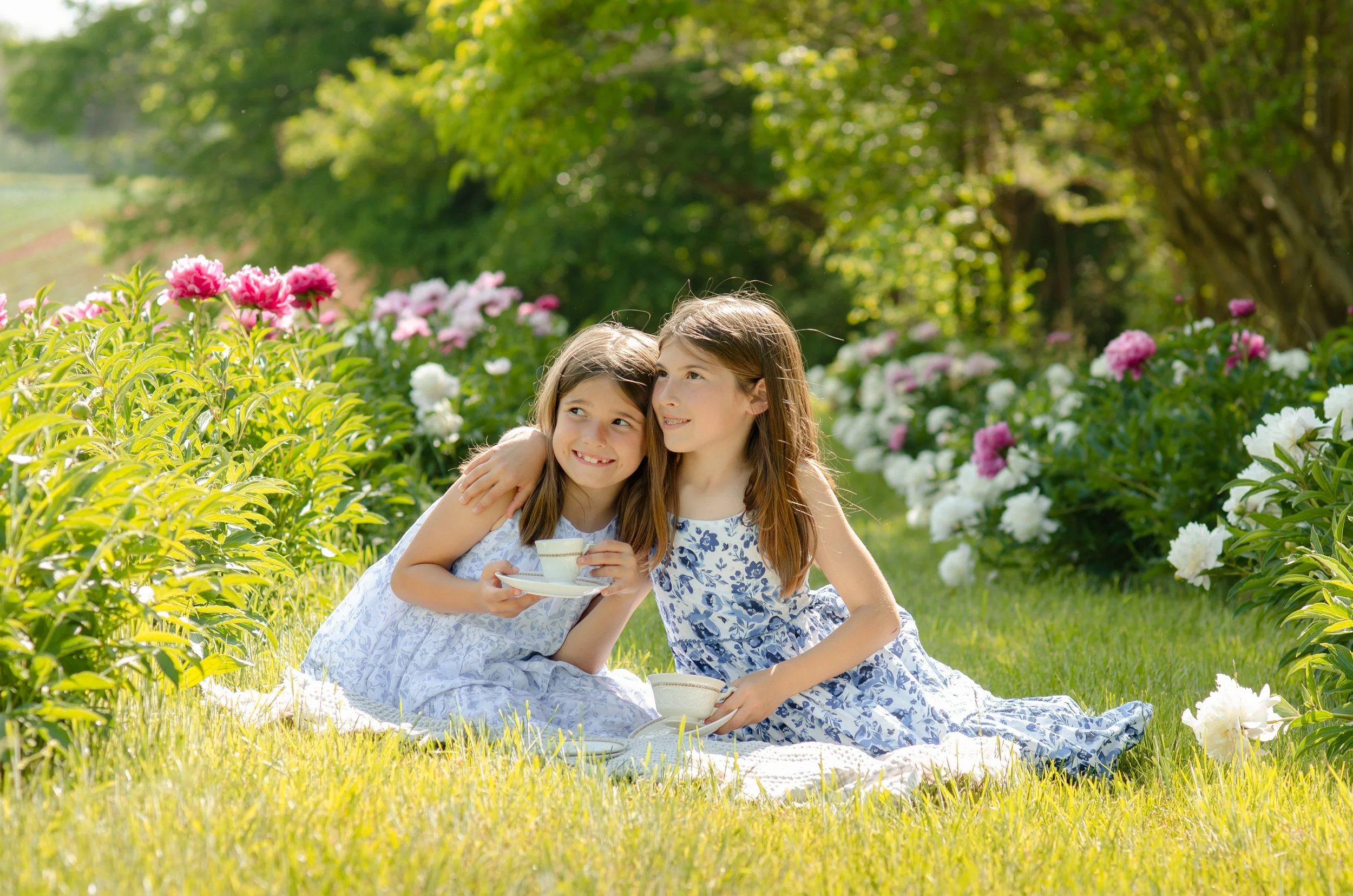 Two sisters laughing together during a tea-party outdoor photoshoot in Knoxville flower field