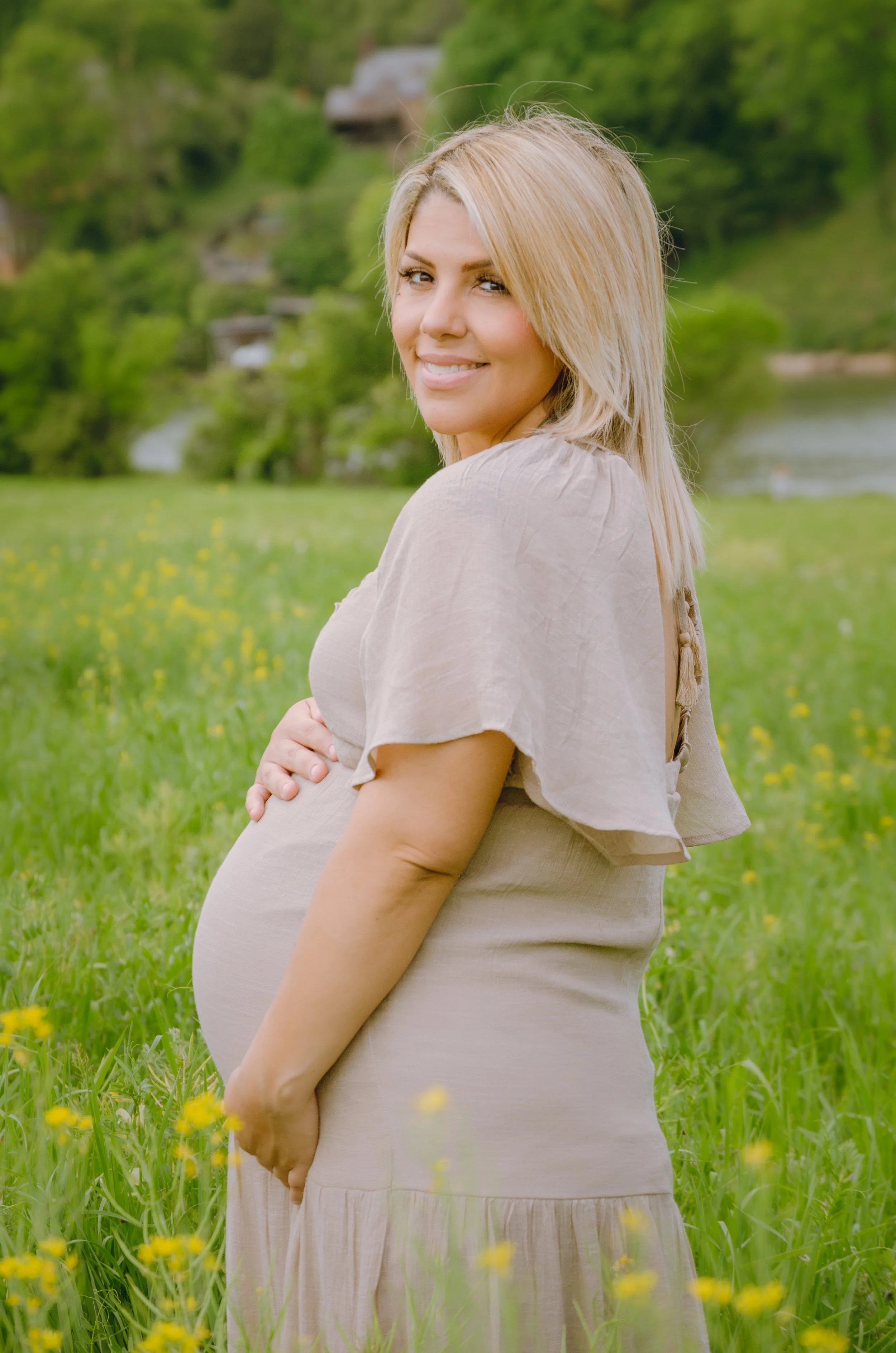 Outdoor maternity session in Knoxville with soft, light, and airy style, with trees and a river in the background.