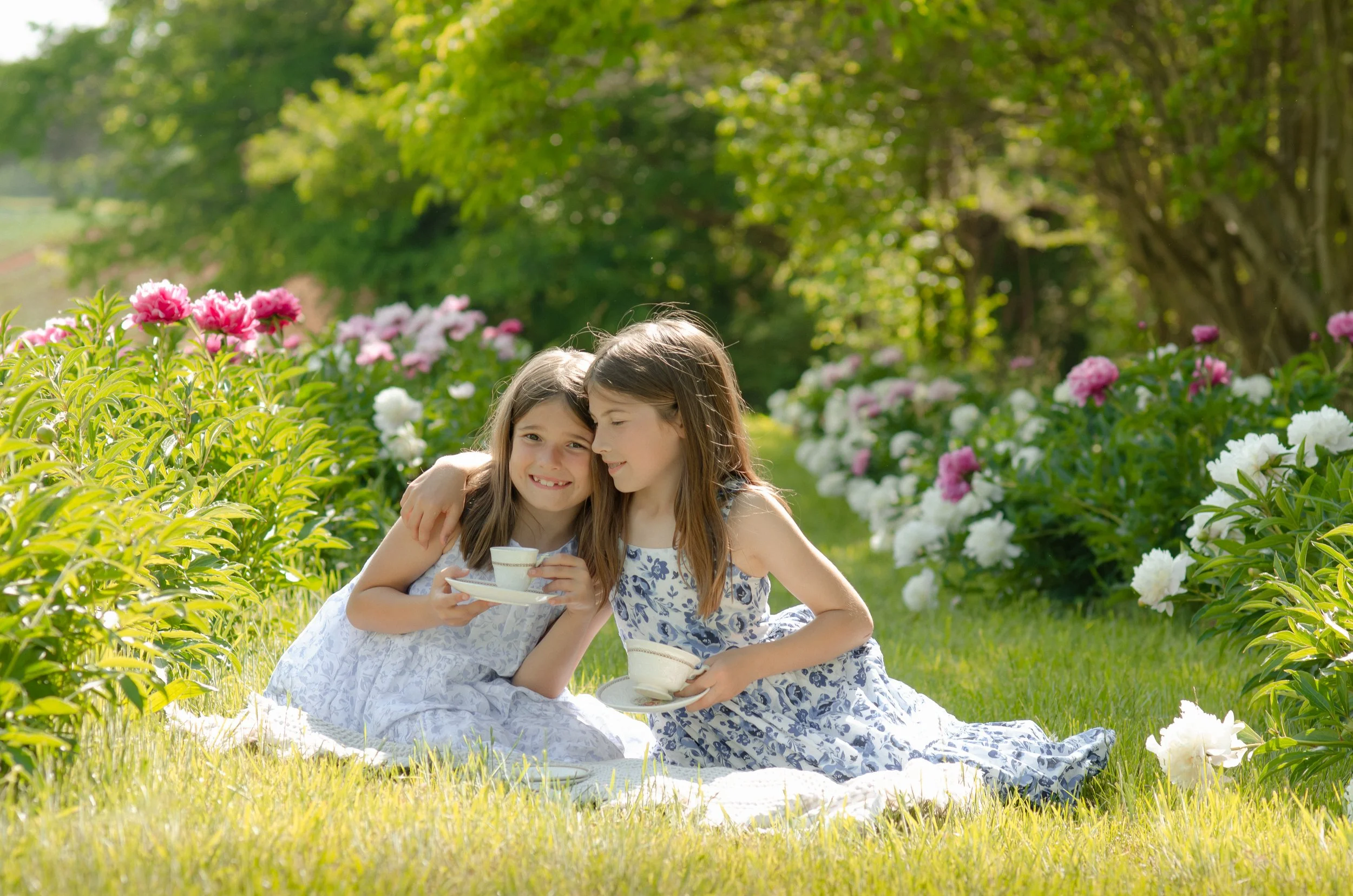 Two sisters laughing together during a tea-party outdoor photoshoot in Knoxville flower field
