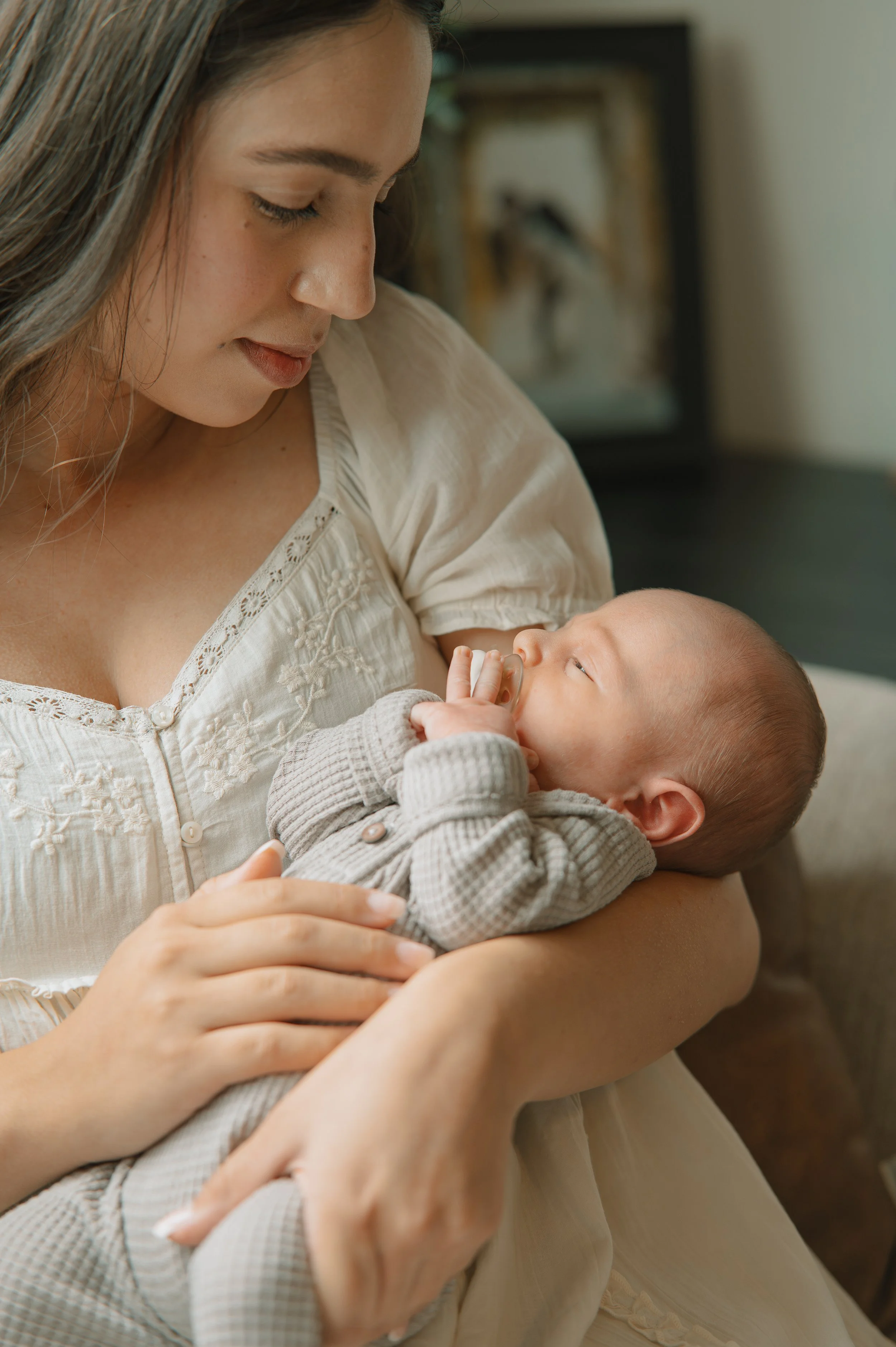 A woman holding a baby in her arms, looking lovingly at the child.