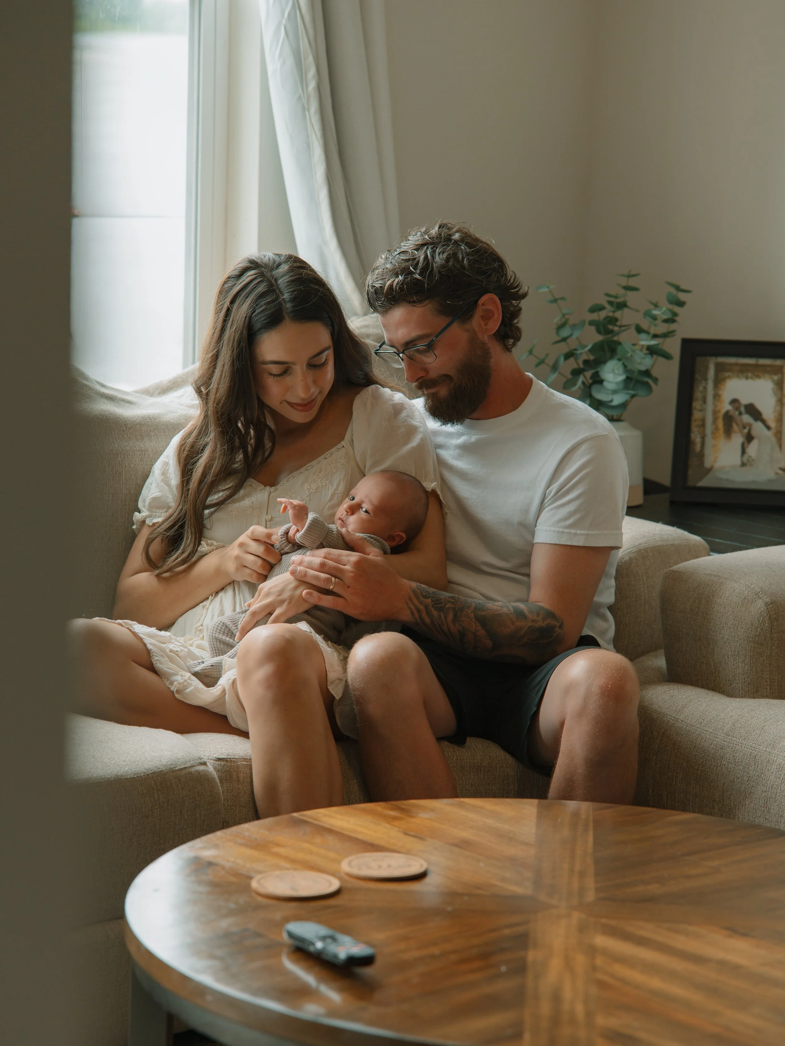 New parents cuddling their newborn during a lifestyle photography session.