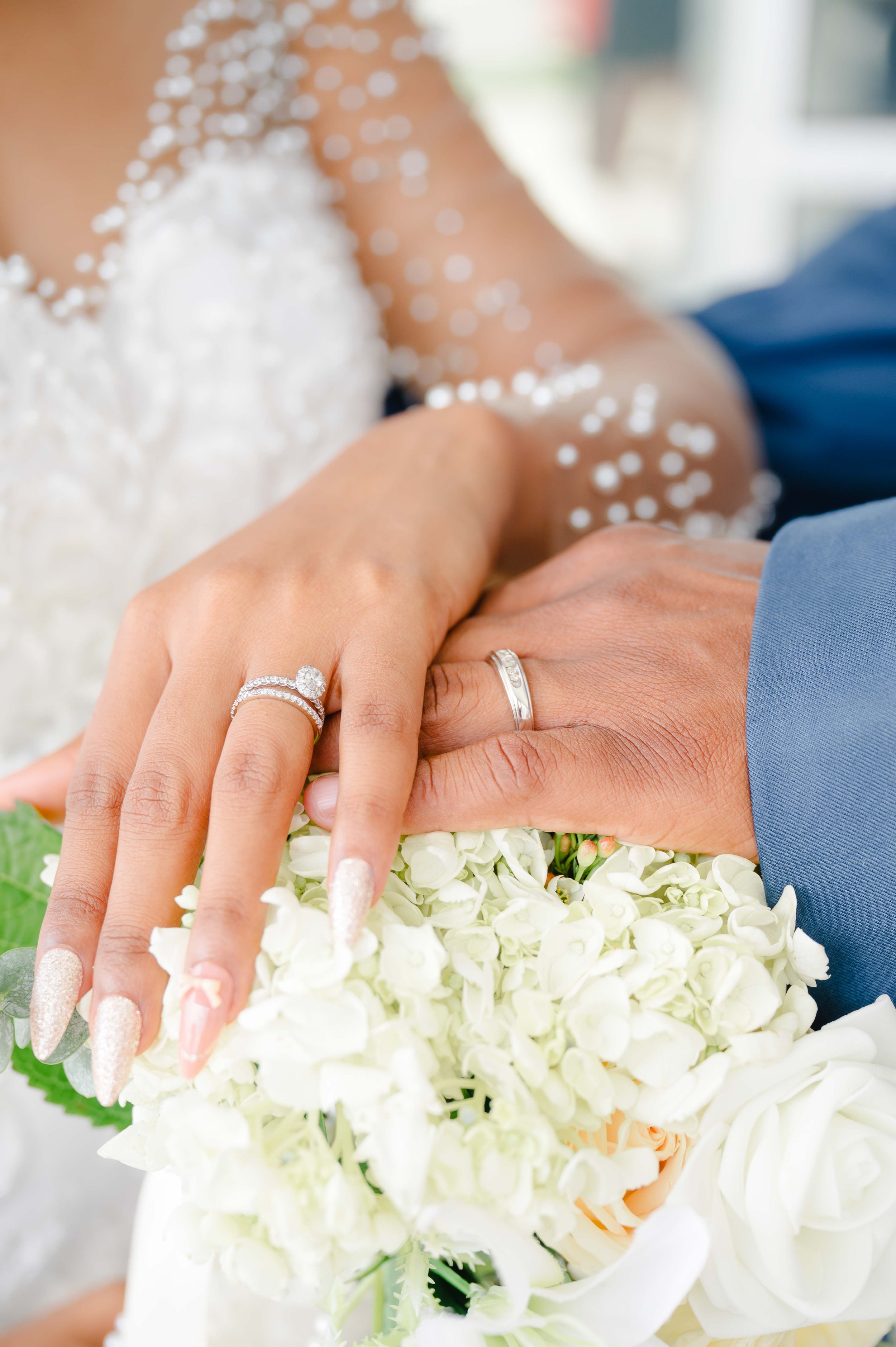 Close-up of a couple's hands showing wedding rings, placed above a bouquet captured by a knoxville wedding Photographer