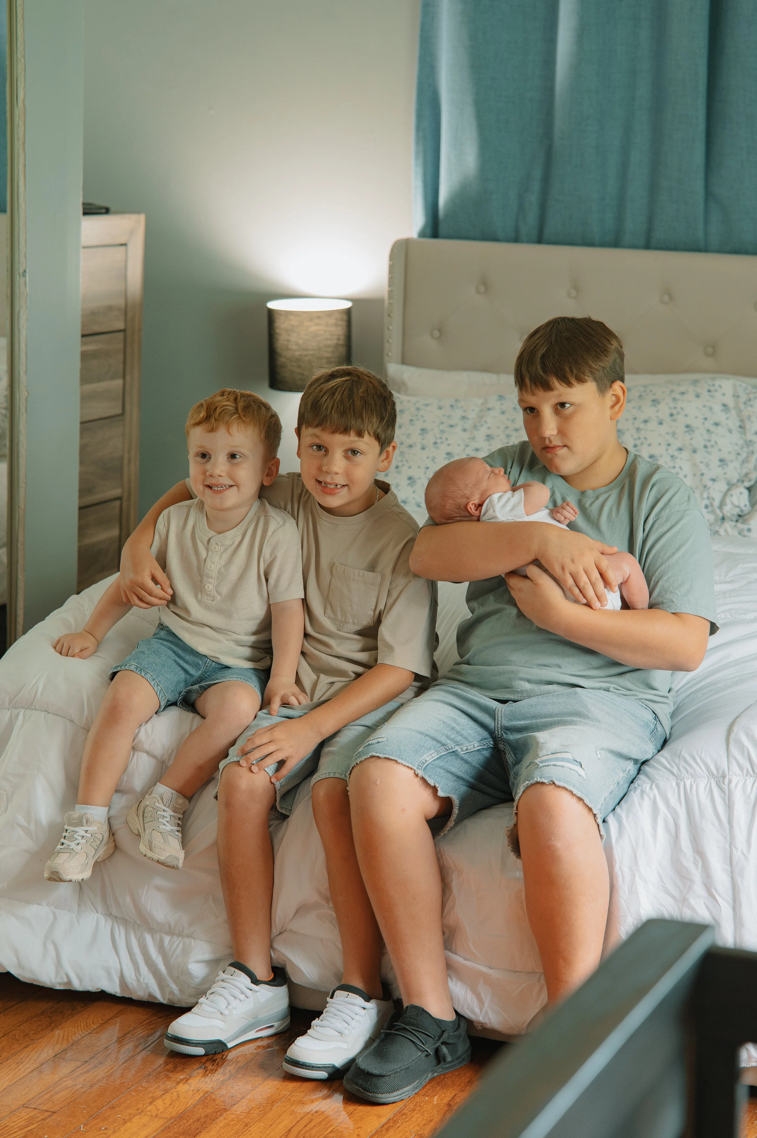 Older brothers meeting and holding their newborn baby brother during a lifestyle newborn session