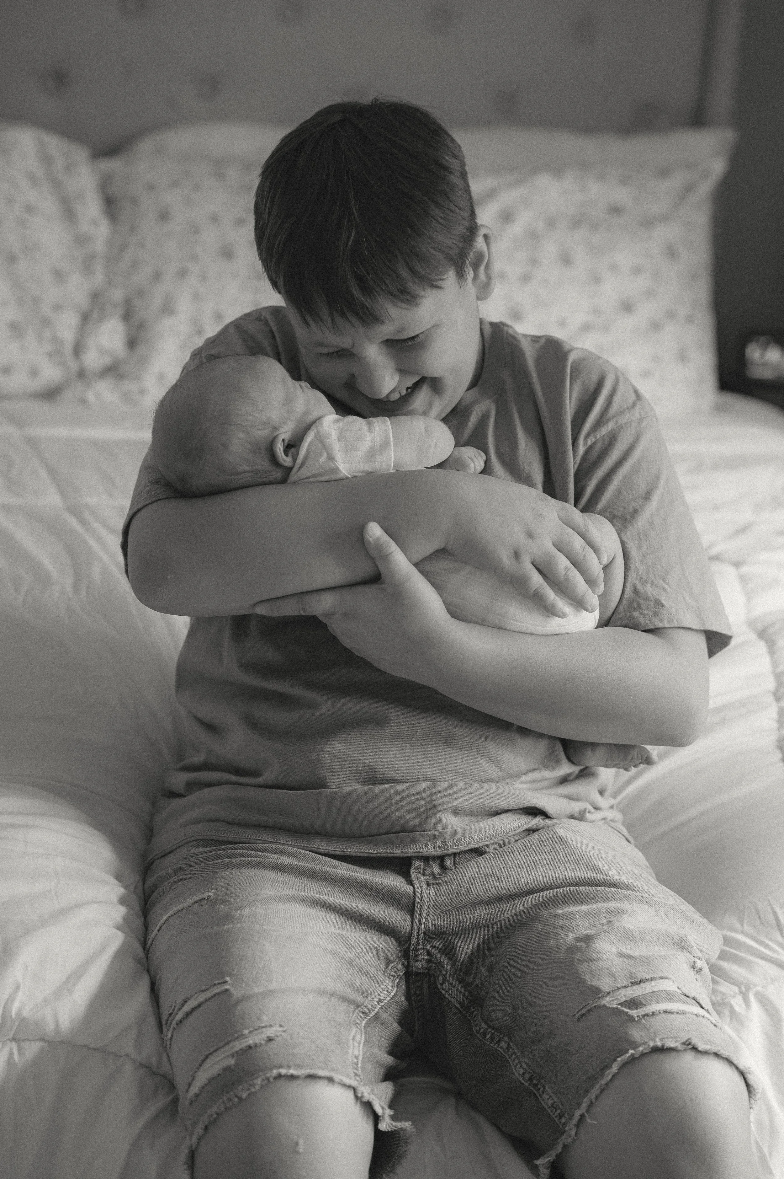 Three older brother hugging his newborn sibling during an in-home newborn photography session