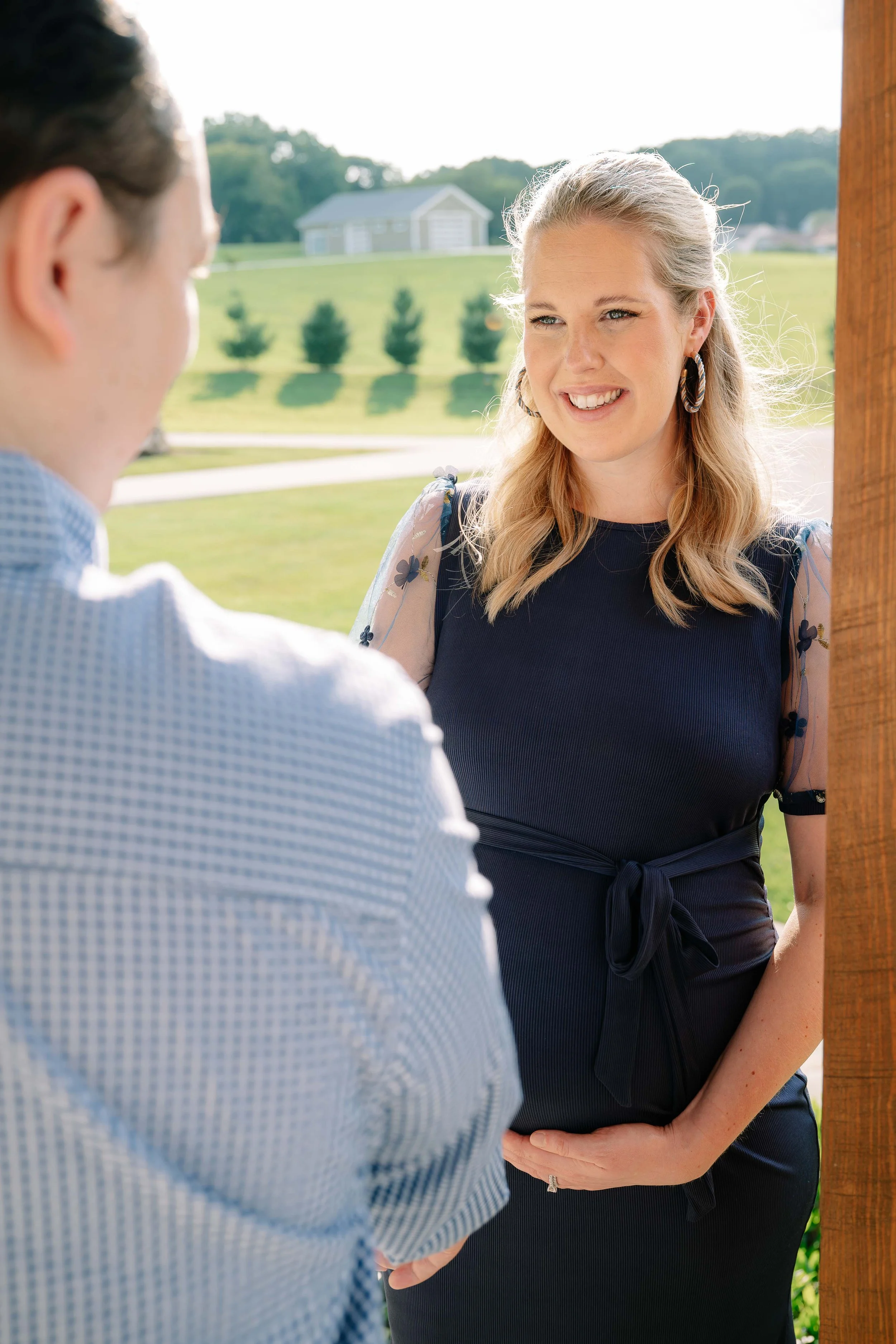 Husband admiring his pregnant wife on a sunlit farmhouse porch during a Maryville maternity session
