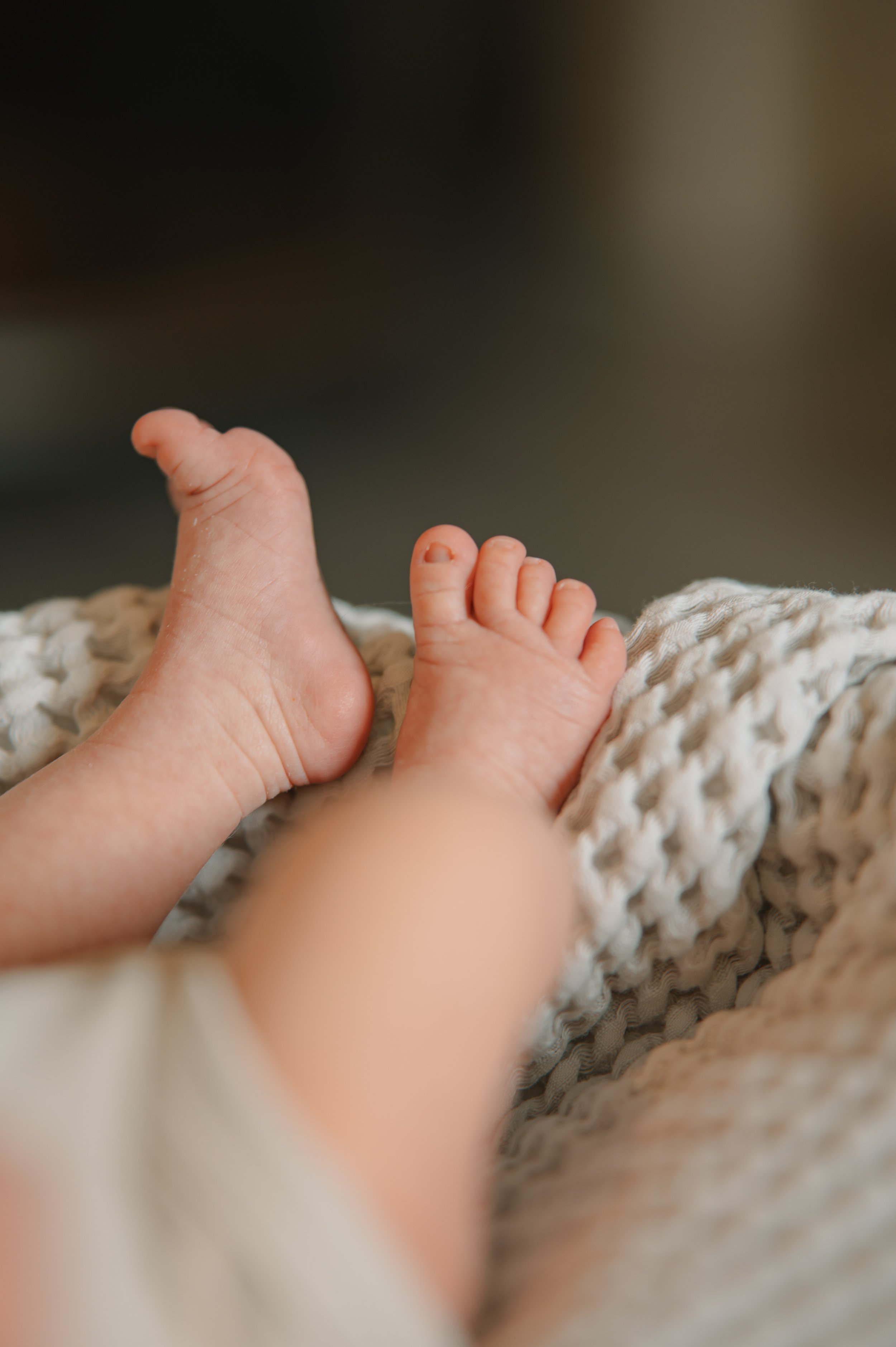 Close-up of two small baby feet resting on a textured blanket.