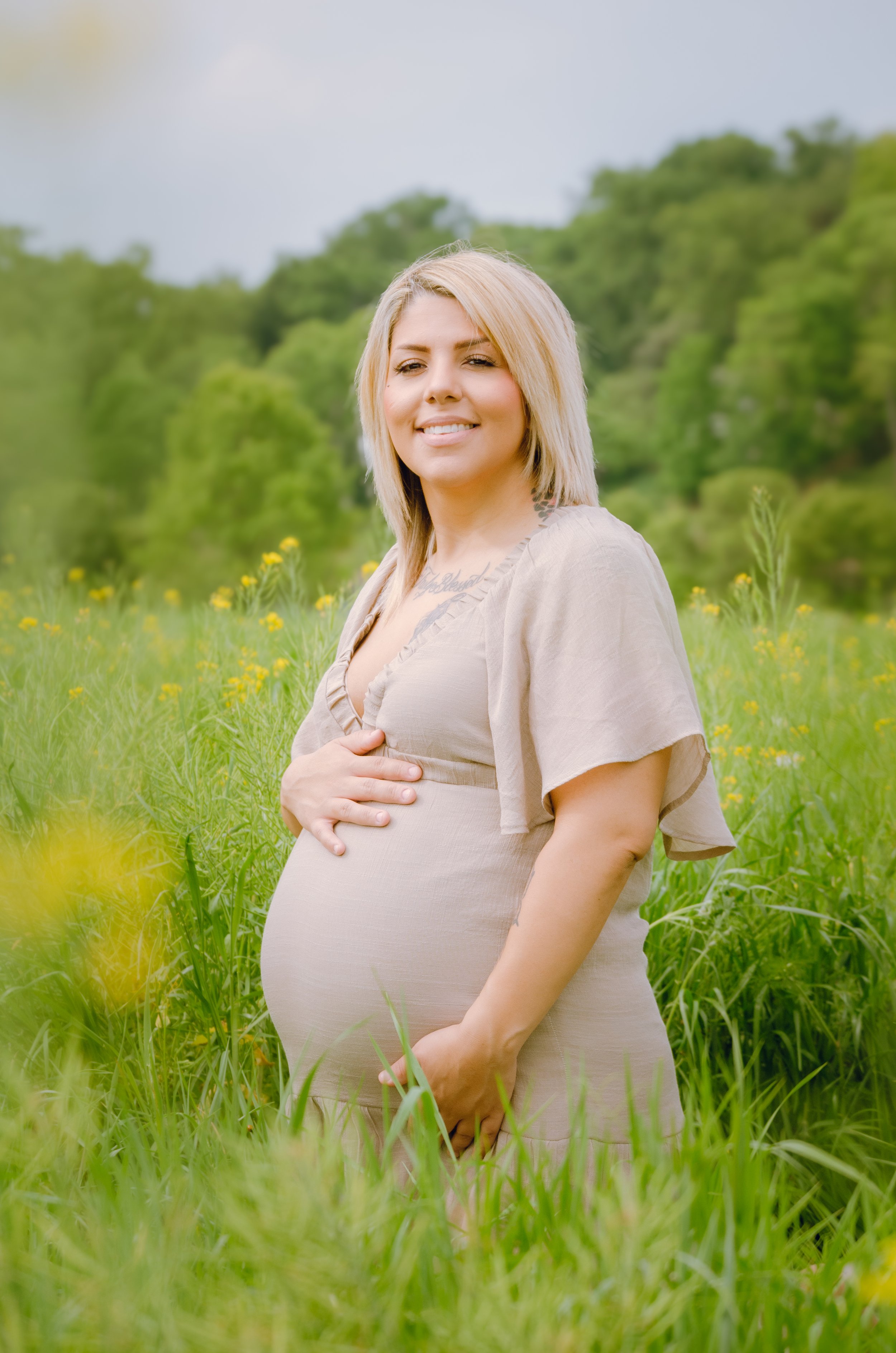 Pregnant mom holding her baby bump in soft evening sunlight in East Tennessee
