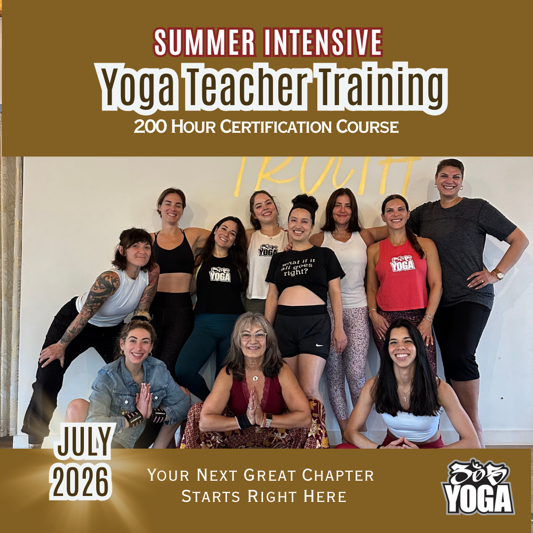 Group of women and one man smiling and posing together at a yoga teacher training event in July 2026. The background shows a white wall with the word 'YOGA' written on it. The event is described as a summer intensive, 200-hour certification course.