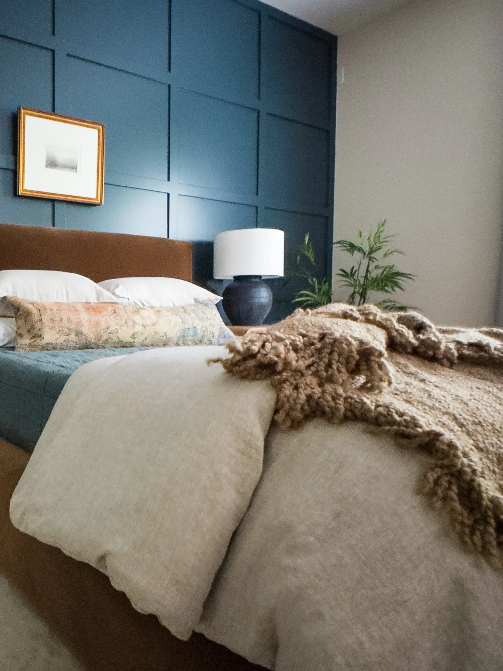 Cinematic guest room with ochre velvet, copper mohair, flax linen, dark blue wall with decorative panels, natural oak nightstands, rustic charcoal lamps, antique brass framed artwork.