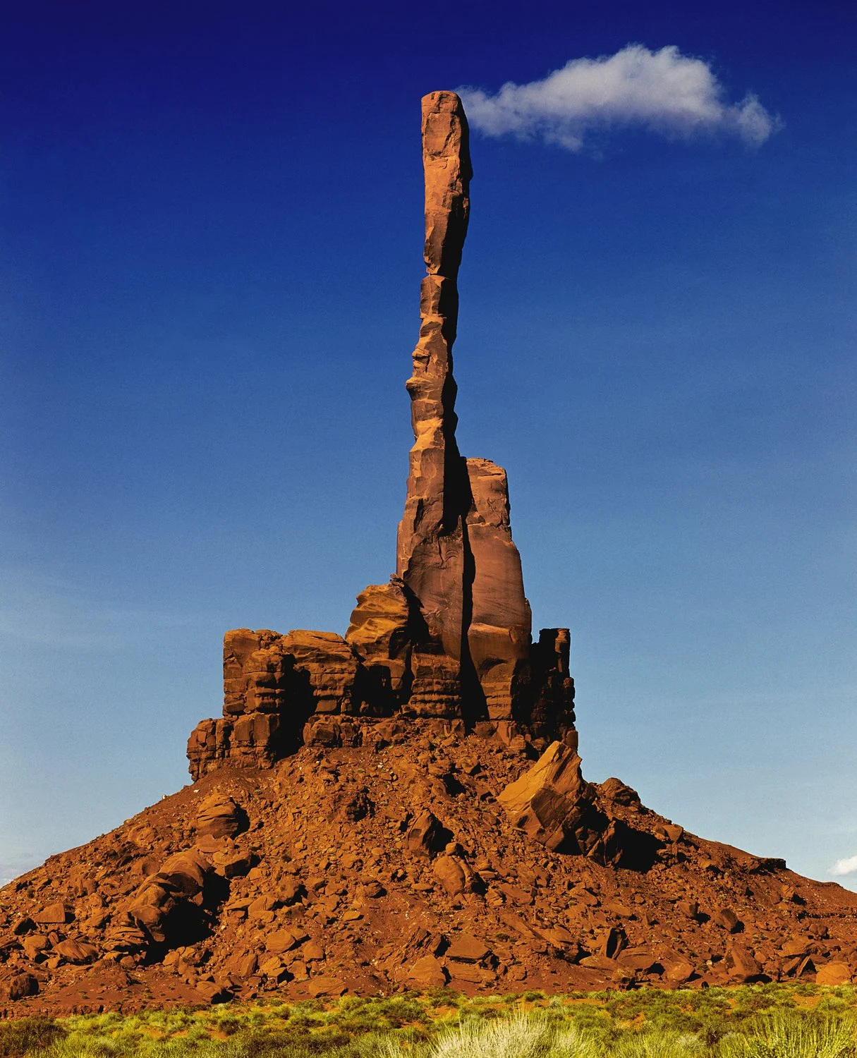 Totem Pole Monument Valley tall sandstone spire rising from desert butte under blue sky