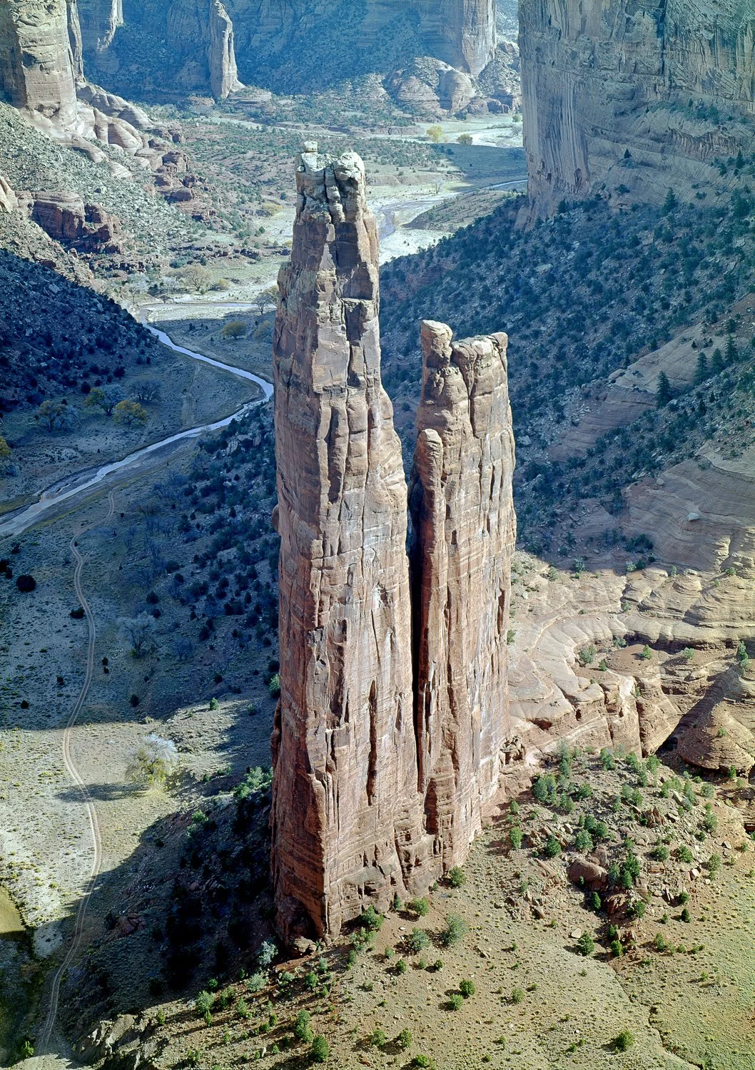 Spider Rock Canyon de Chelly AZ showing tall sandstone spire rising from desert canyon floor with winding road below