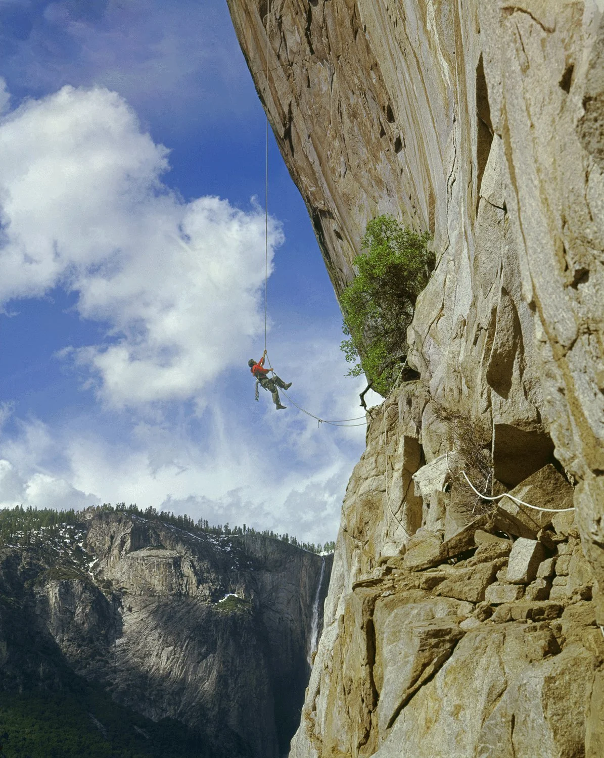 The Air Apparent, 1961. Warren Harding ascends a fixed line on the dramatically overhanging West Face of the Leaning Tower in Yosemite Valley. Relying heavily on drilled placements, this airy route was first climbed by Harding, Glen Denny and Al Macd