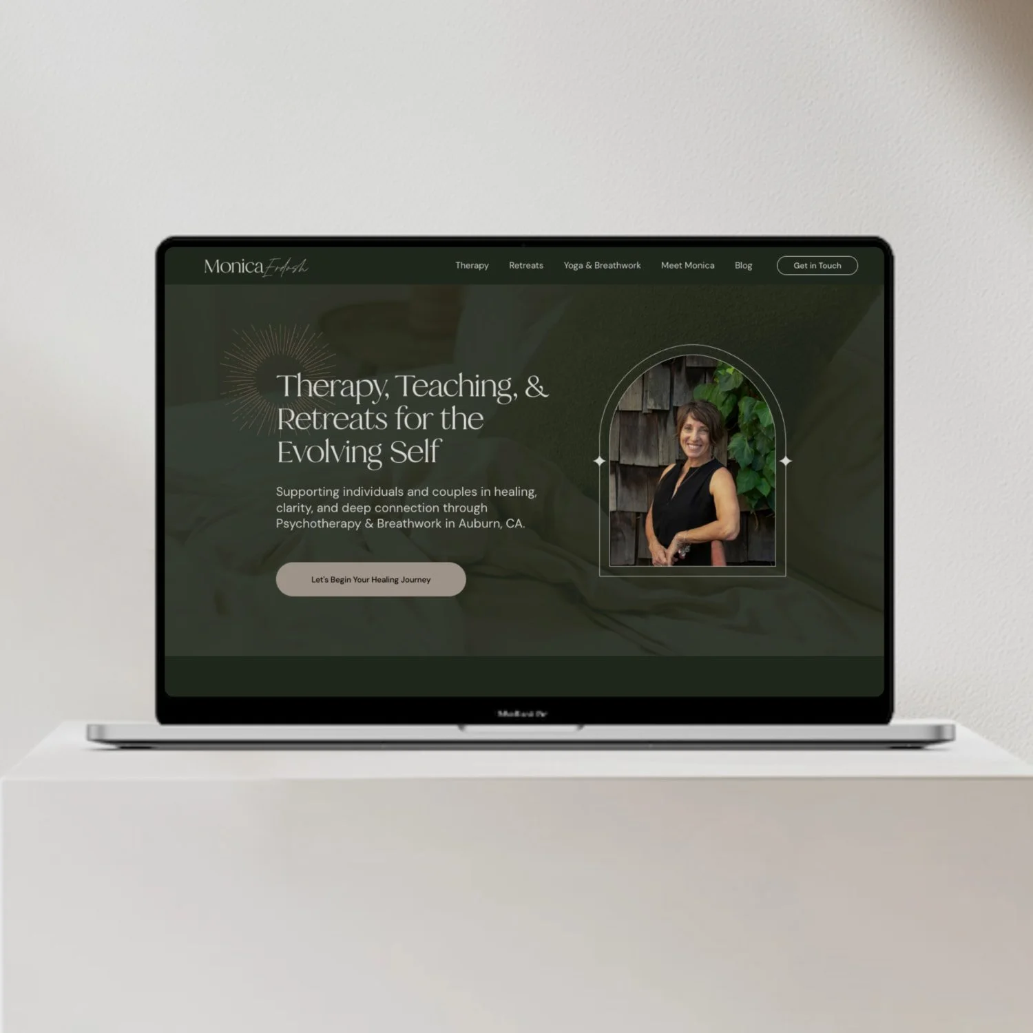 Laptop displaying a website for therapy, retreats, yoga, and breathwork with a woman's photo and a call-to-action button.