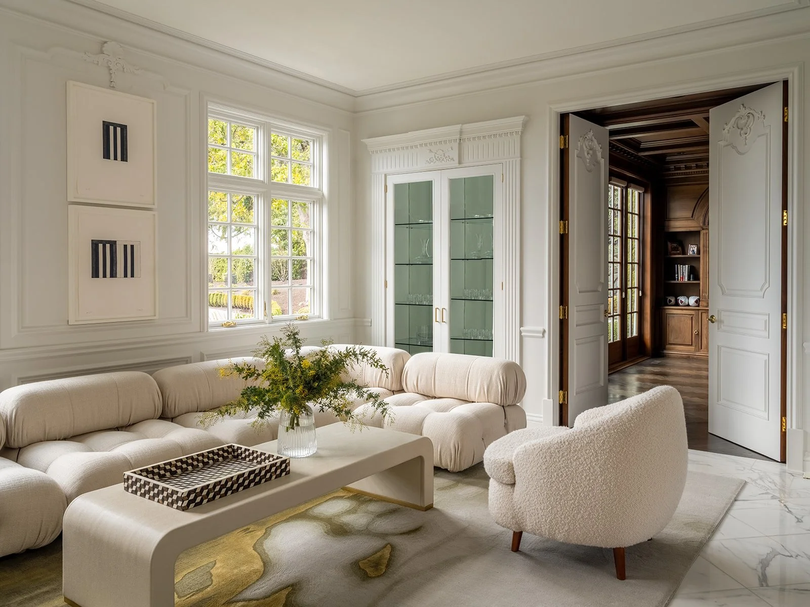 A bright and elegant living room with white walls, large windows, a cream sectional sofa - Rucon Build
