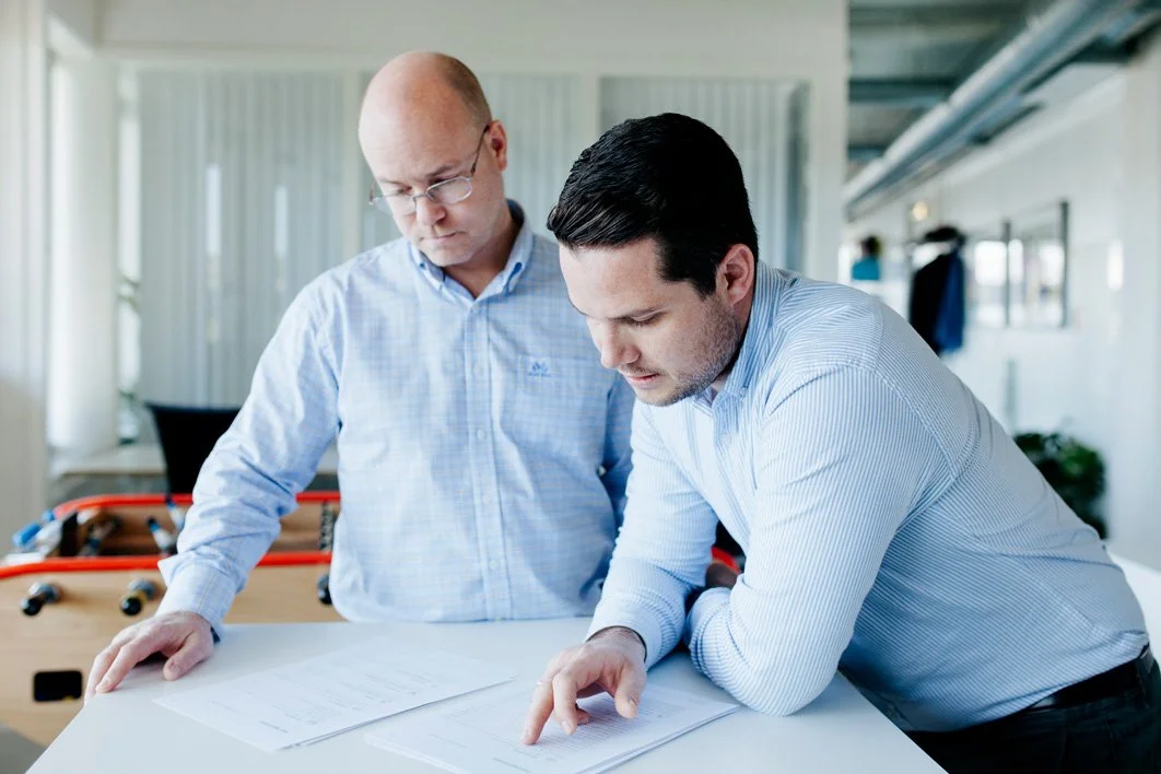 To menn i kontor, gjennomgår dokumenter på bord i et mødelokale.