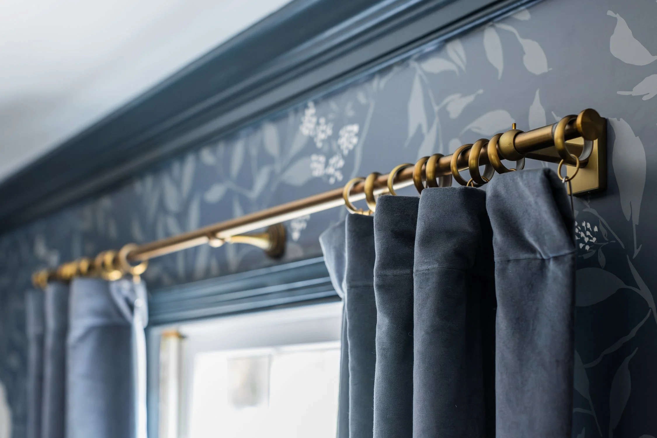 Brass curtain rod offers a pretty contrast to the dark curtains and wallpaper.