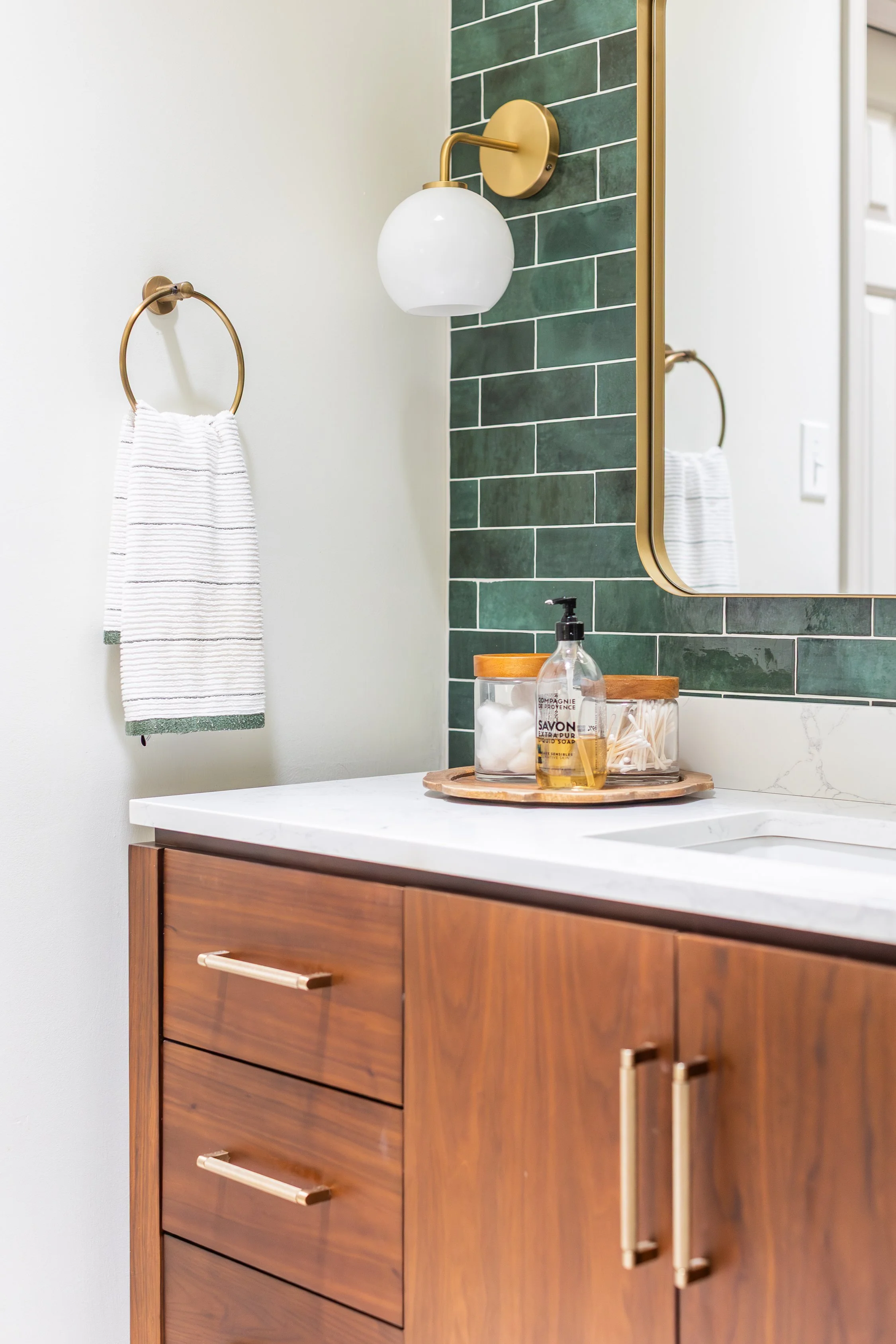 Green tile, brass fixtures, wood vanity