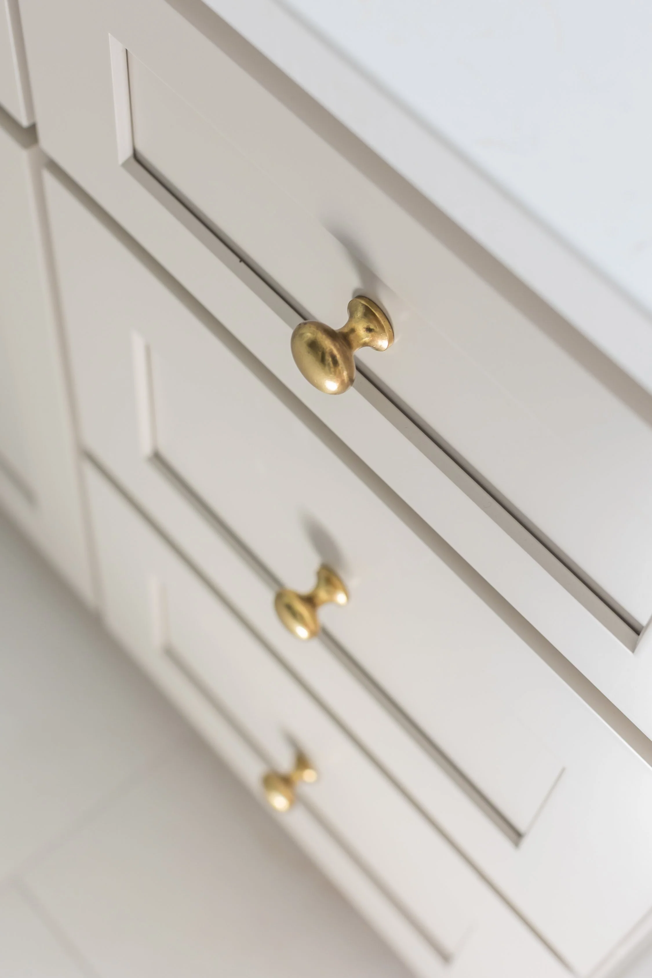 Close-up of a white cabinet drawer with a gold-colored round knob.