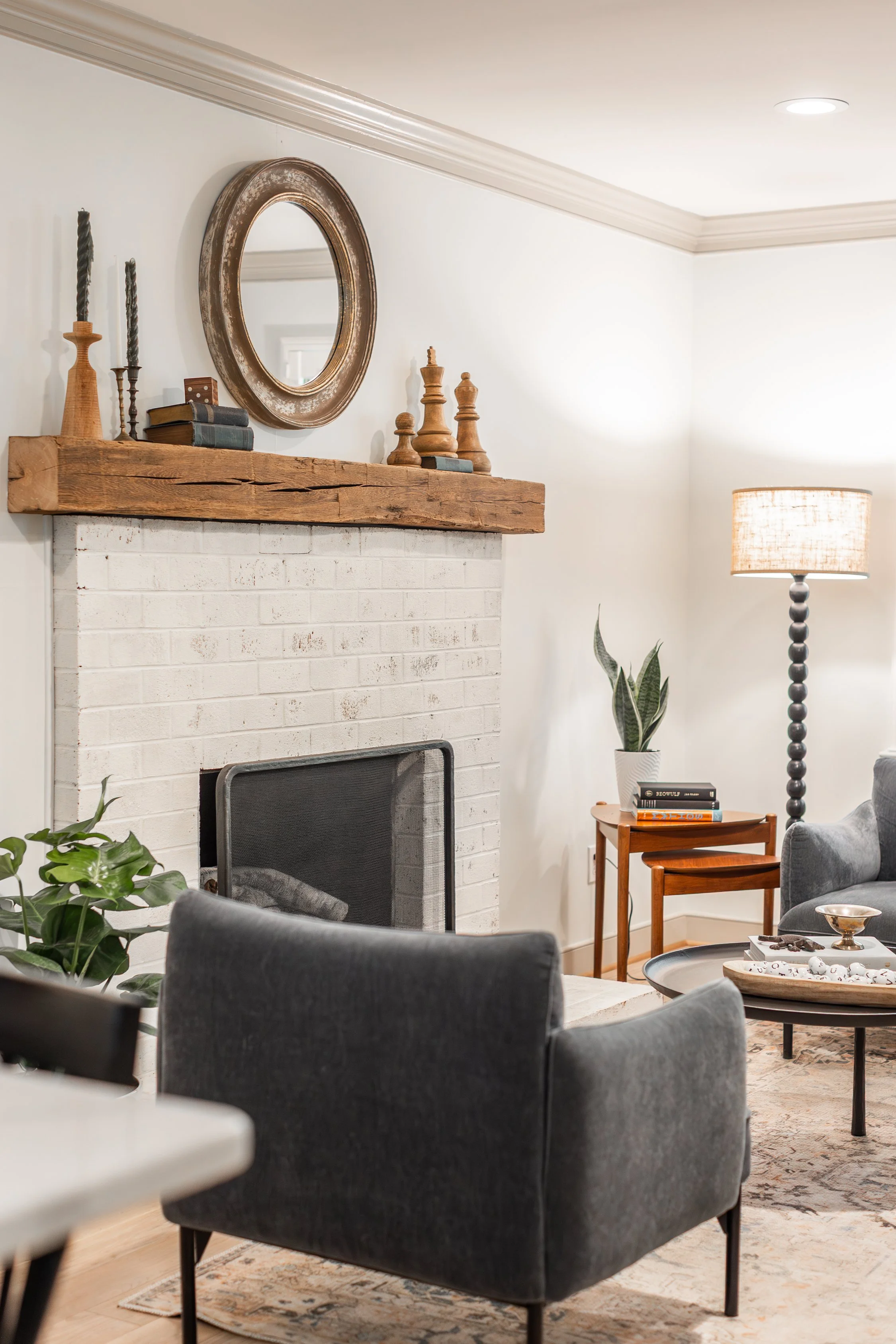Family room using textures to create interest with rustic mantel, wood tones, and velvet.