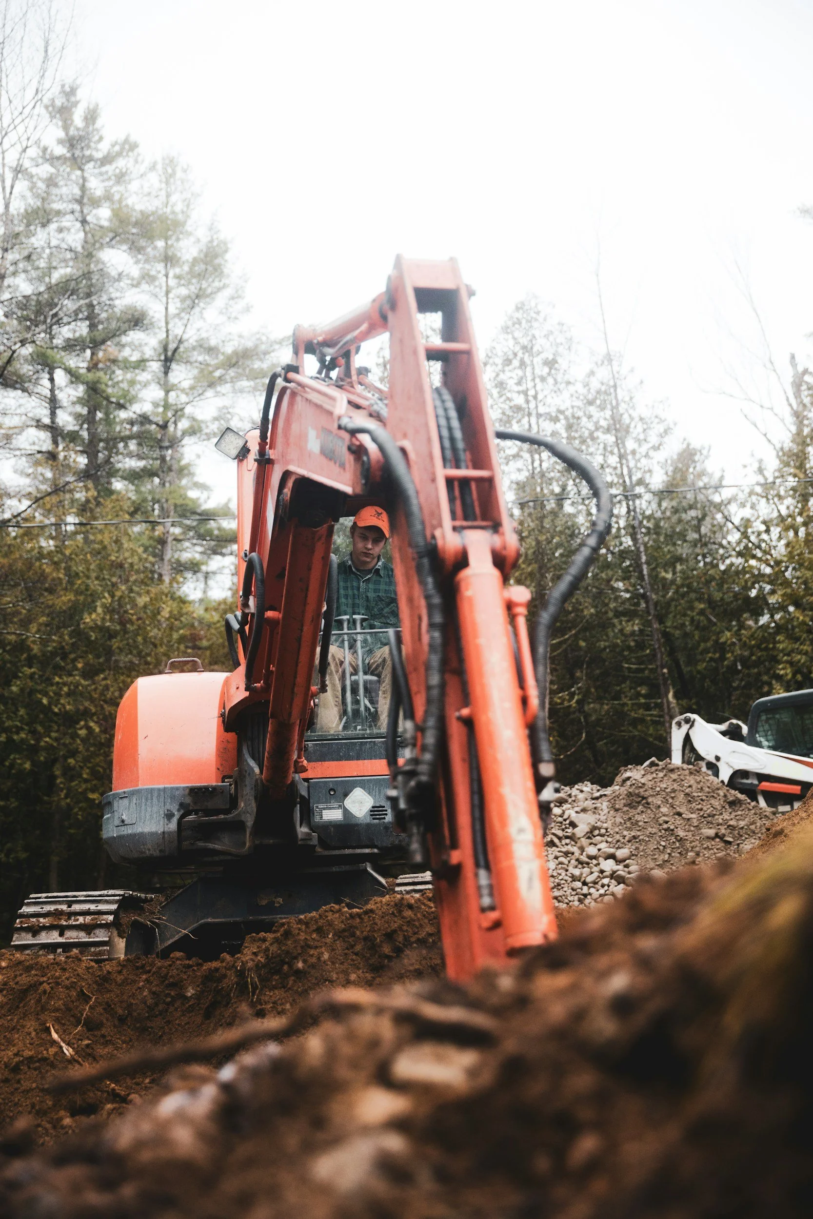 An operating orange excavator on a dirt construction site, excavating and digging sewer lines.