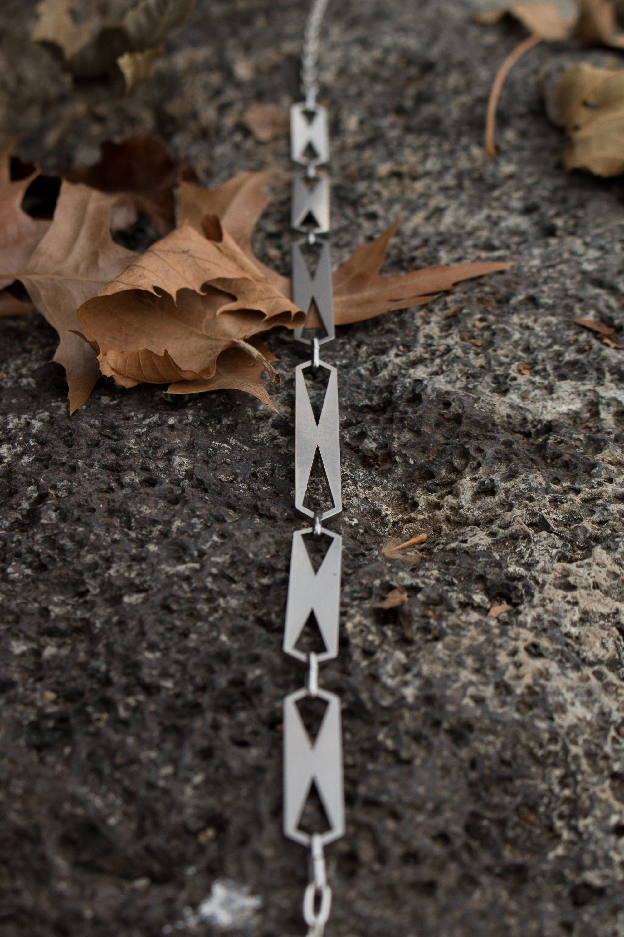 Close angled view of the linked plates and cut-out geometry against weathered stone.