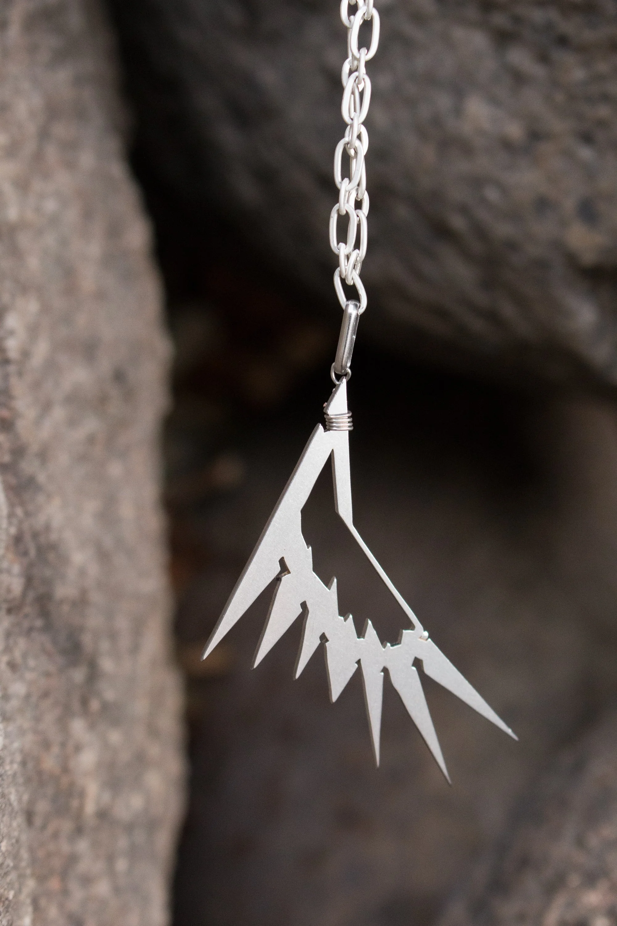 Older Artwork by Apotheosis Jewelry Arts, an Art Deco Wing motif hanging from a silver plated chain.