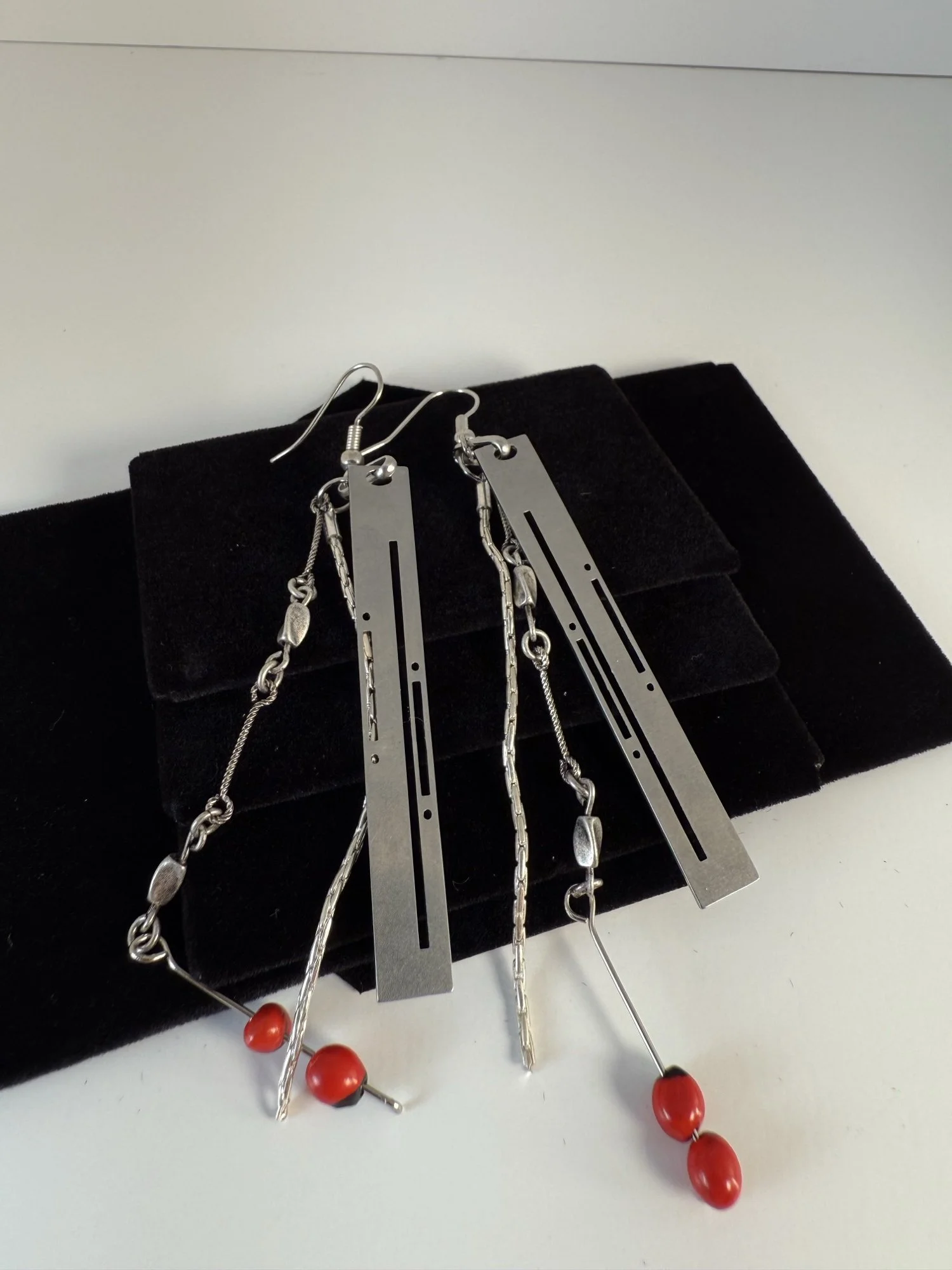 The same earrings laid flat on black velvet, showing full chain length and bead placement.