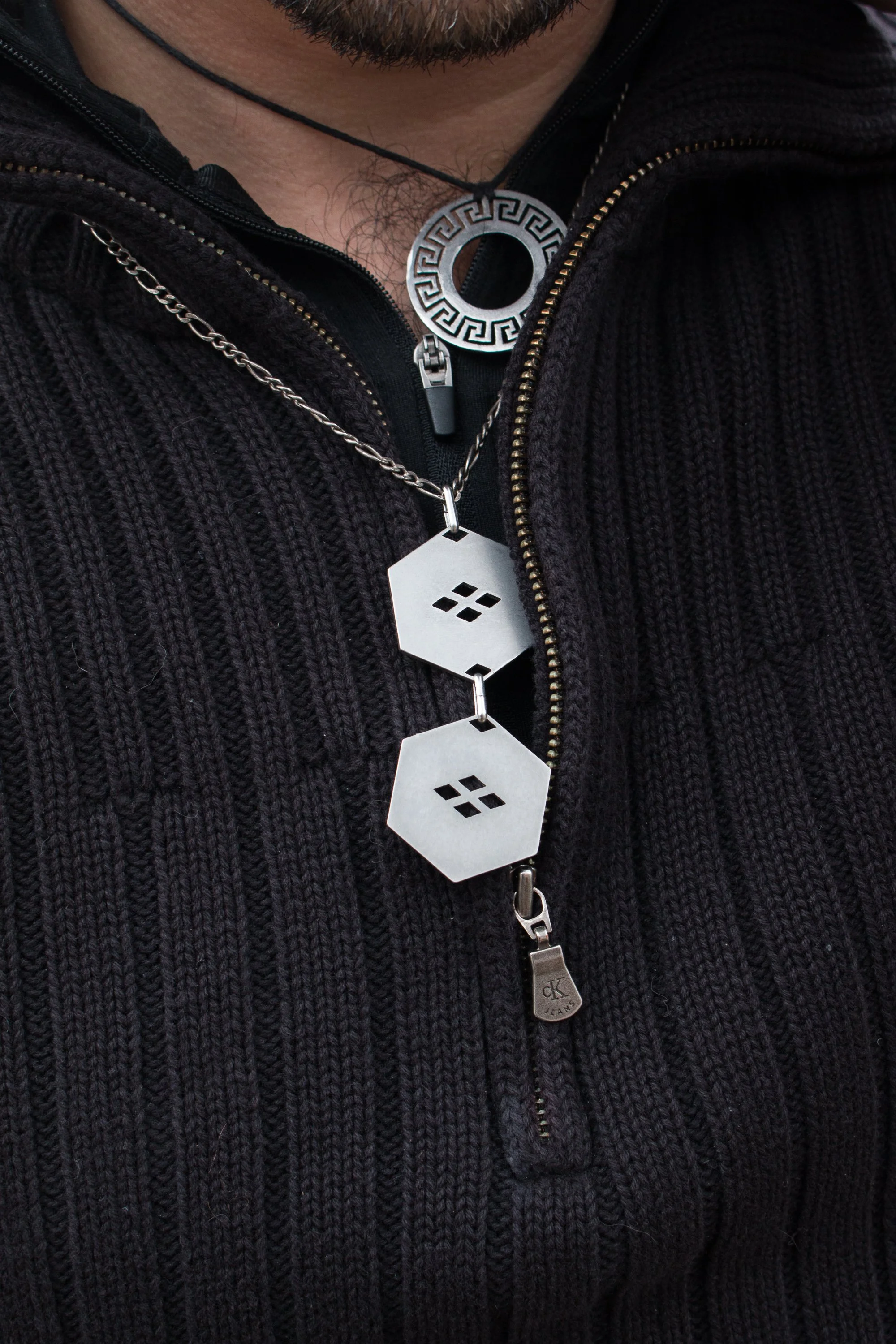 The pendant worn on a black knit sweater, showing scale and how the hexagons rest at the chest.