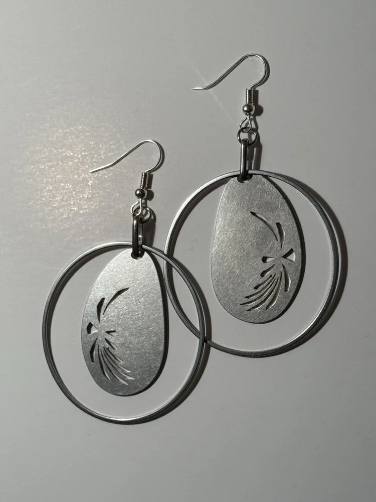 Close view of the oval medallion and radiant cut-out motif, showing the brushed surface of the stainless steel.