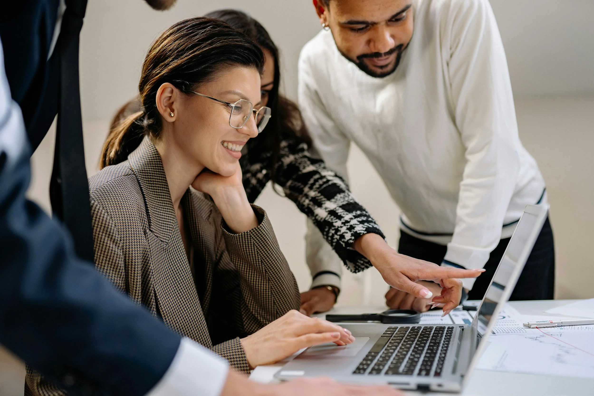 People working together around a laptop in a meeting room.